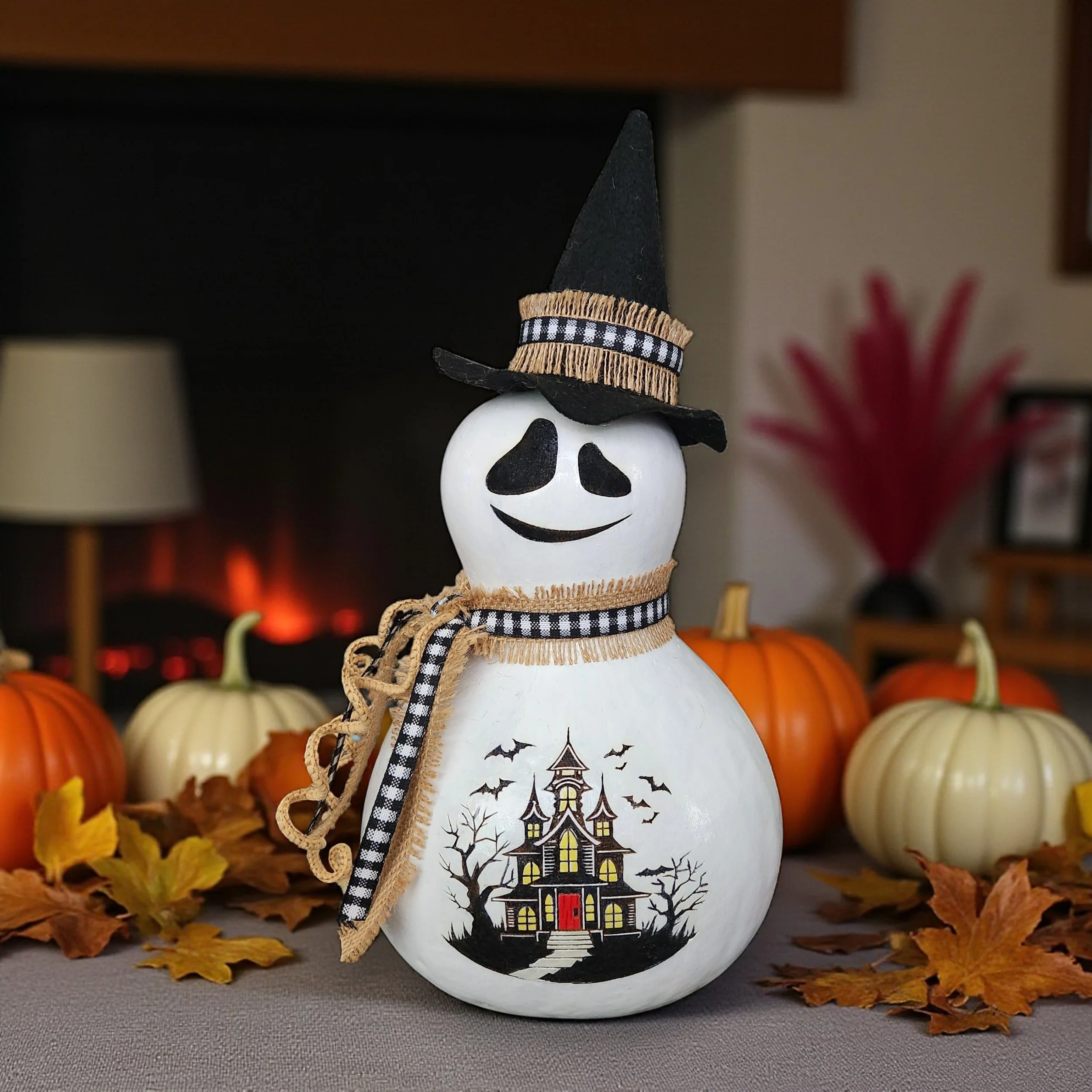 Closeup view of Ghost Witch with laser engraved and painted haunted house on its belly in a festive fall display.