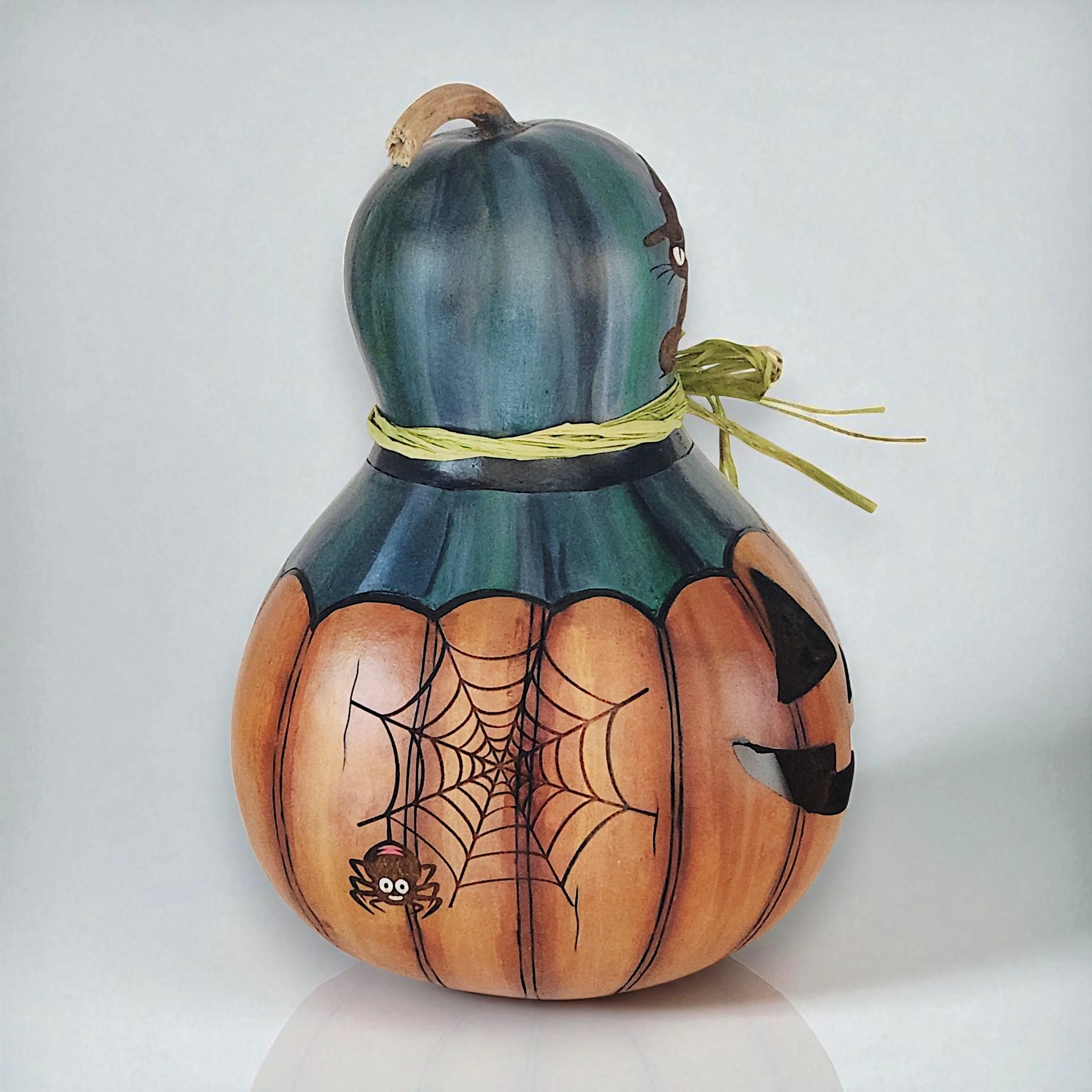 Side view of Jack-o-lantern gourd with laser engraved spider and web with additional details wood burned by hand.