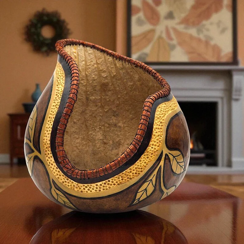 Handcrafted gourd bowl with carved leaf design, shown from a front angle on a neutral background.