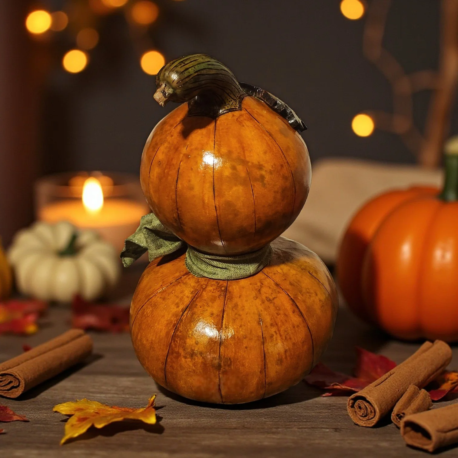 Rear view of stacked jack-o-lantern decor showing smooth pumpkin backs and surrounding fall foliage.