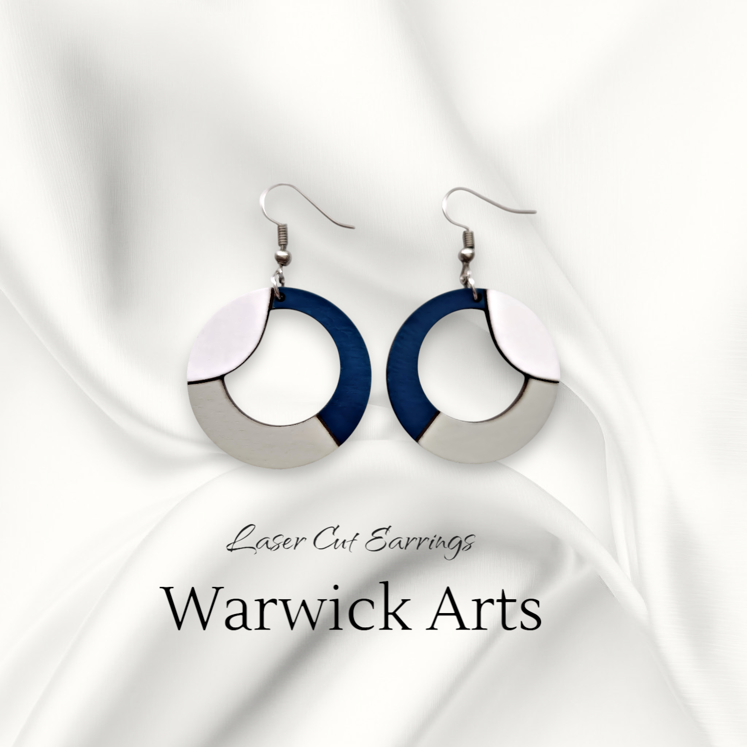 Laser-cut earrings in crisp navy blue, white, and soft grey wood, shaped in a circular wave pattern with sterling silver ear wire.