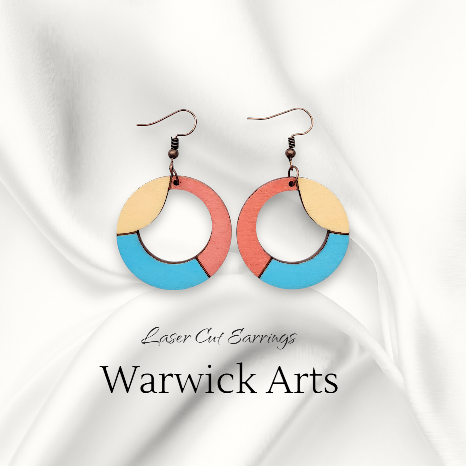 Vibrant laser-cut earrings in golden yellow, coral pink, and vivid blue, with a bold circular wave design and copper ear wire.
