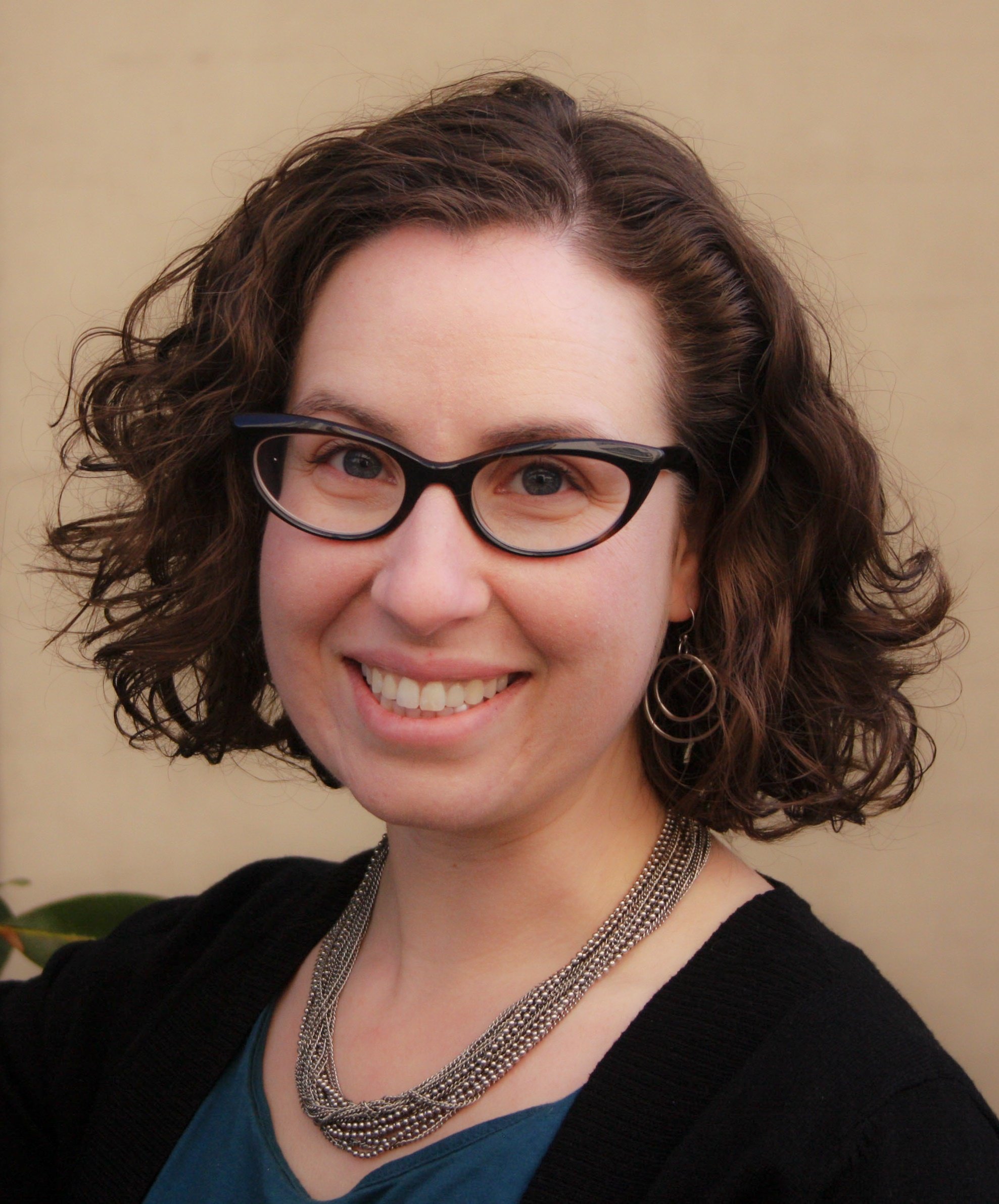 Photo of Lisa Rosenzweig, PhD, psychologist in New York City, smiling warmly outdoors with soft natural light and a hint of greenery. Specializes in therapy for illness, pain, and medical stress.