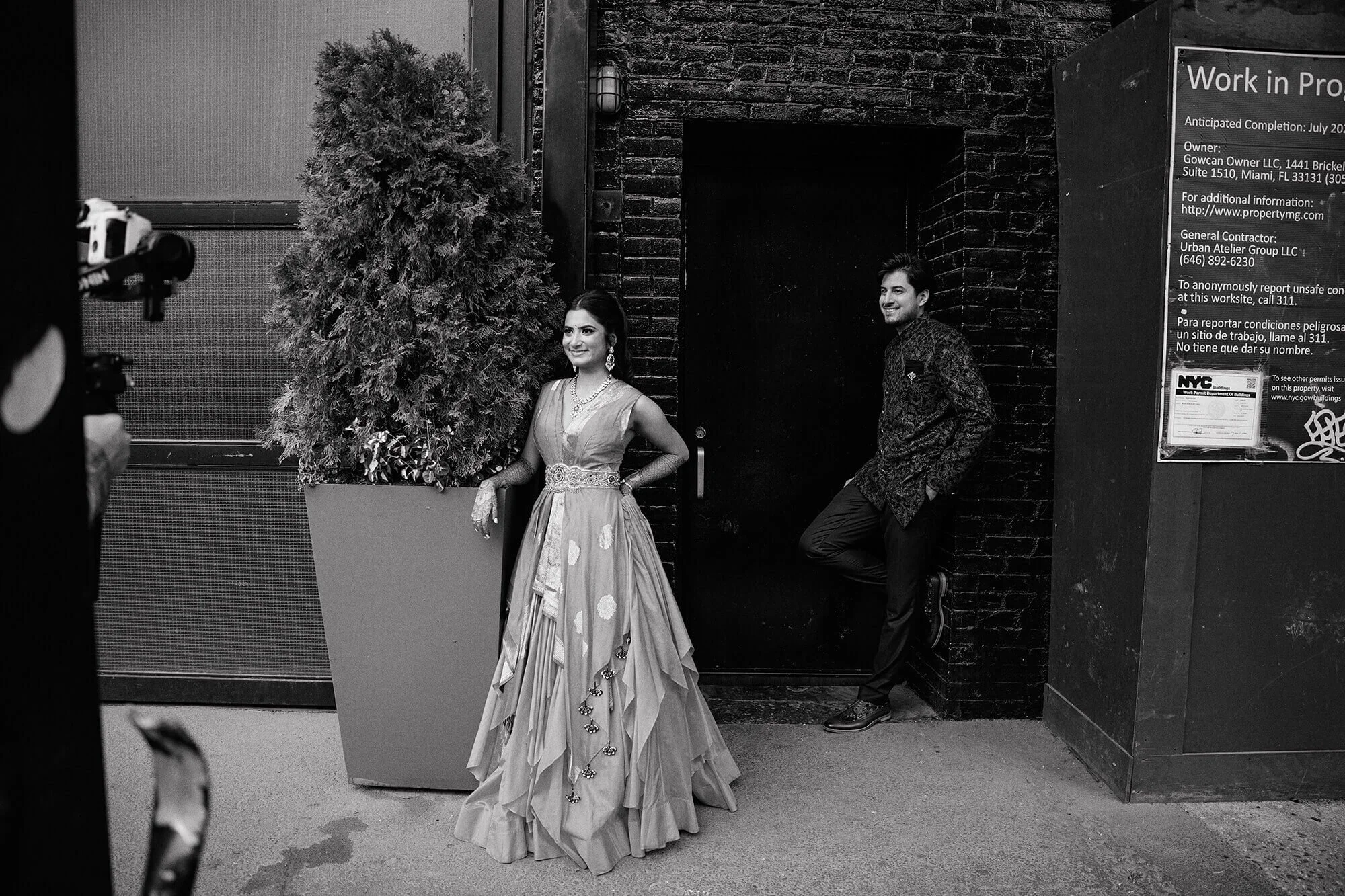 Black and white portrait of the couple against a striking textured brick wall