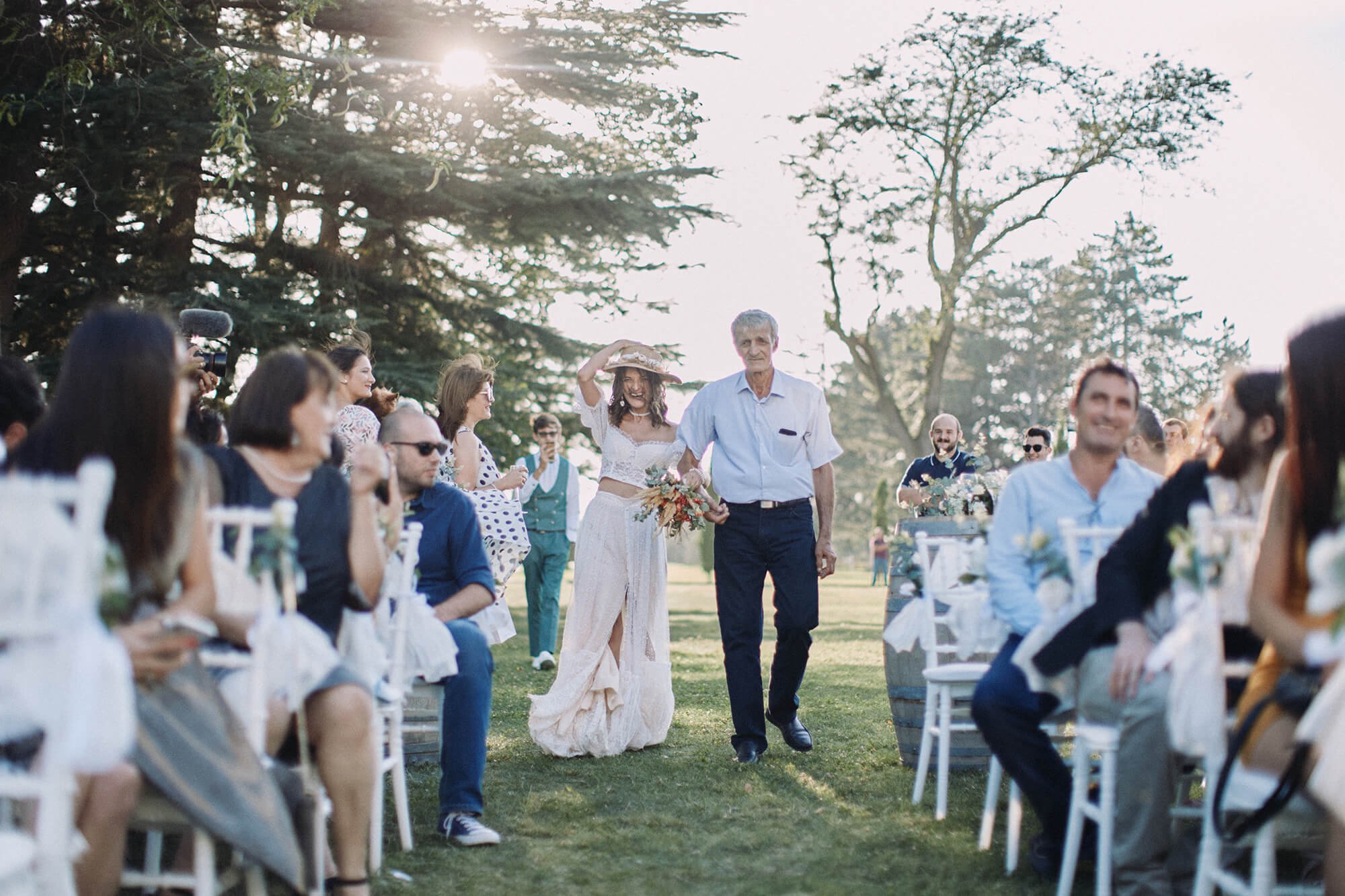 Bride walking down the aisle with her father outdoors