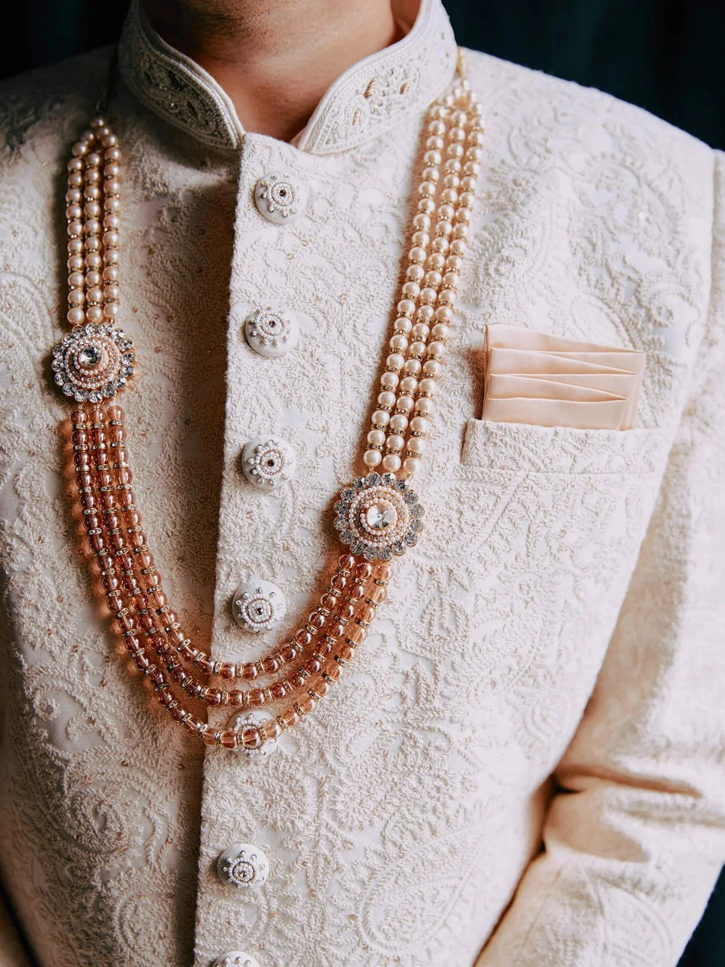 Detail shot of the groom's wedding sherwani with a beaded necklace and pocket square