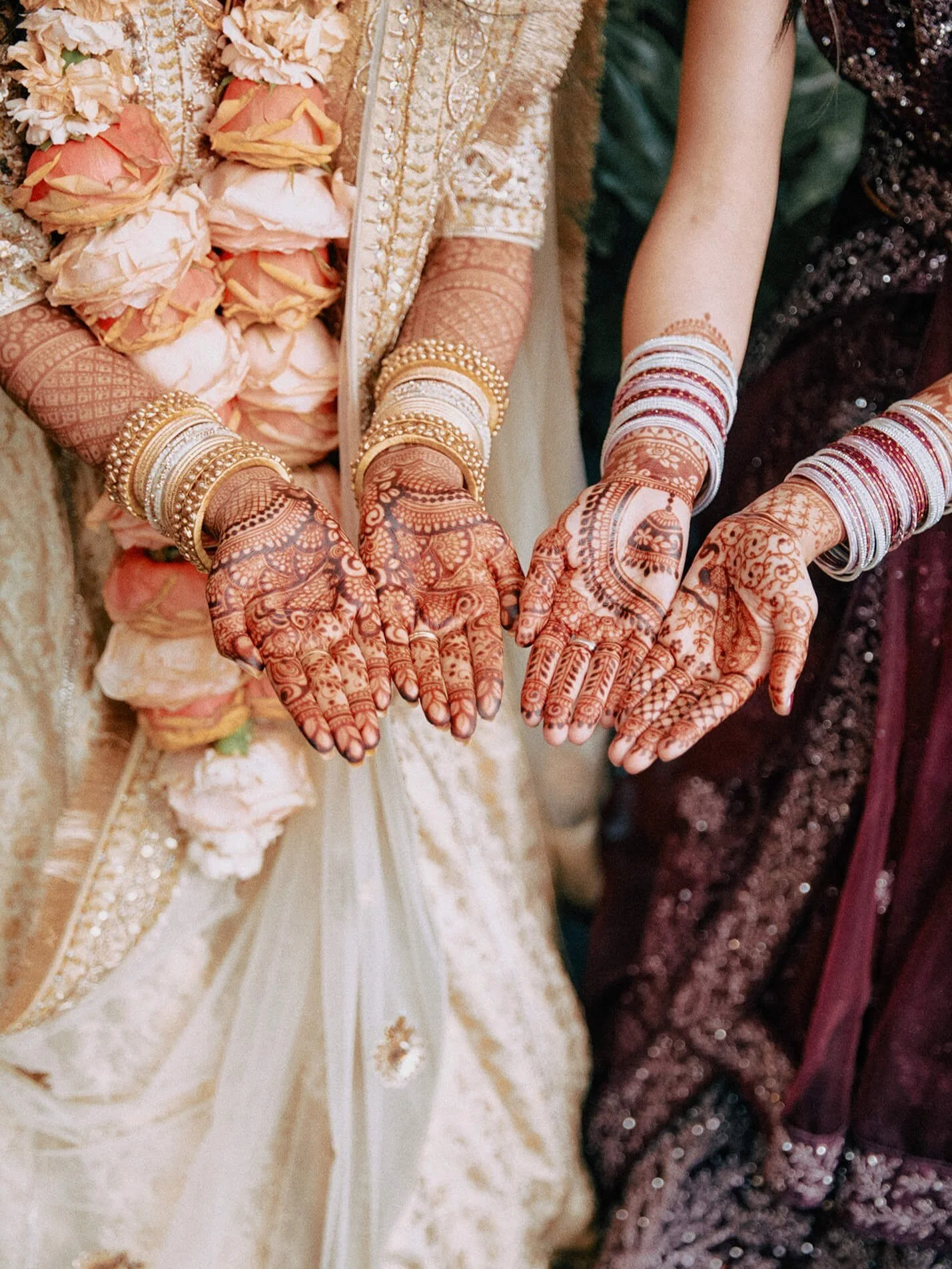 Close-up of the bride's hands adorned with intricate mehndi designs and bangles.