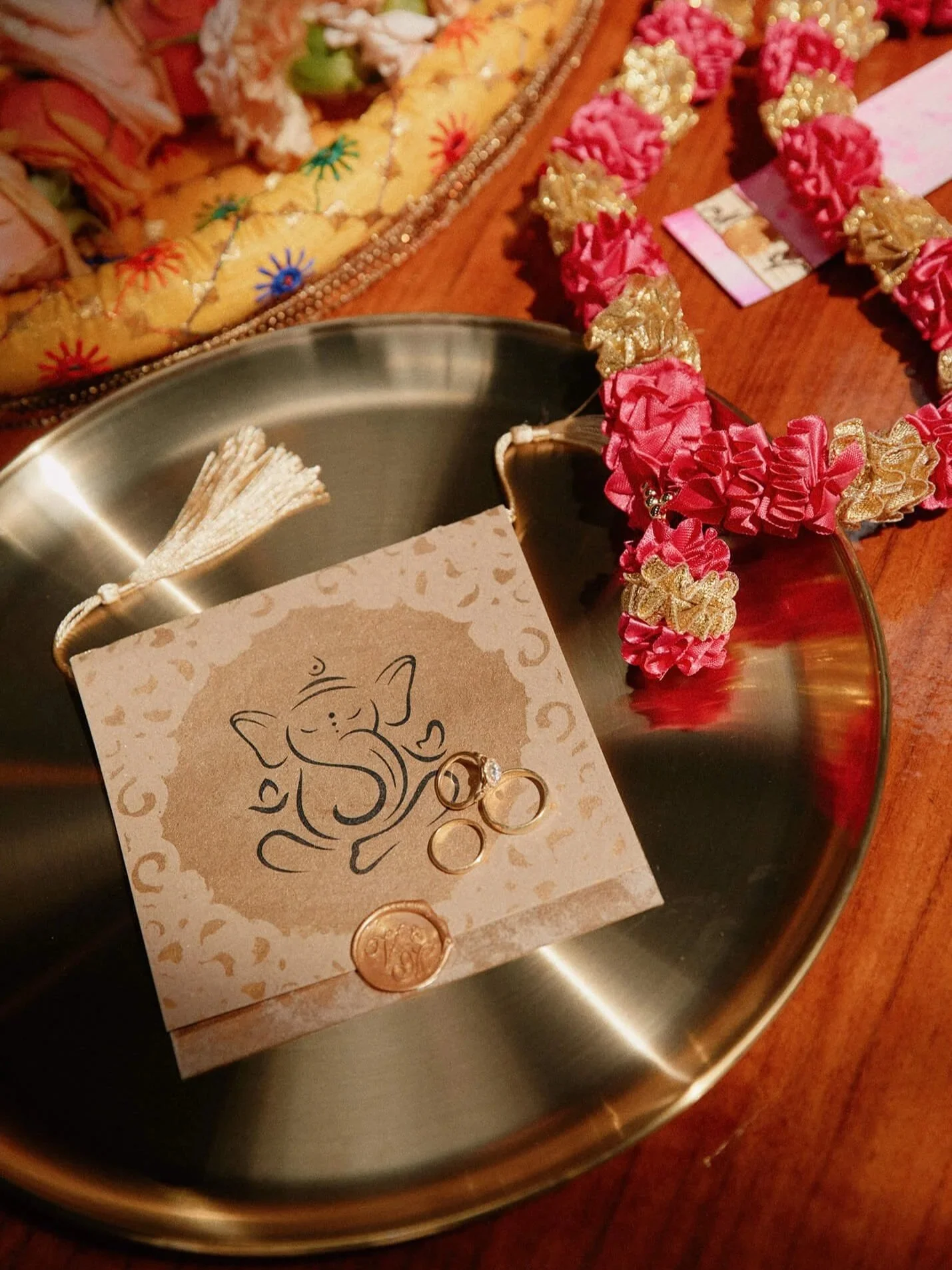Close-up of wedding rings on a Ganesha-themed invitation card, a beautiful Indian wedding detail