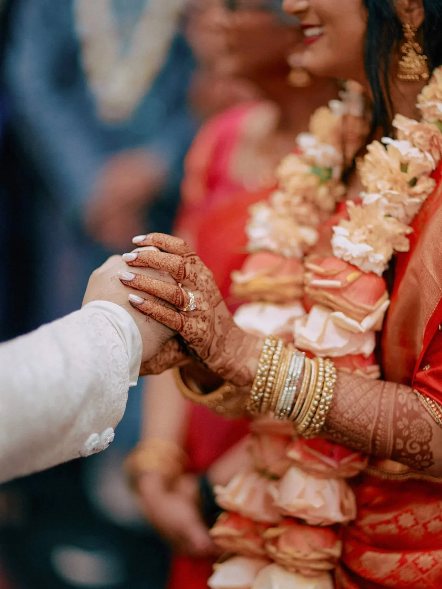 The couple’s hands are adorned with traditional garlands during a sacred wedding ritual