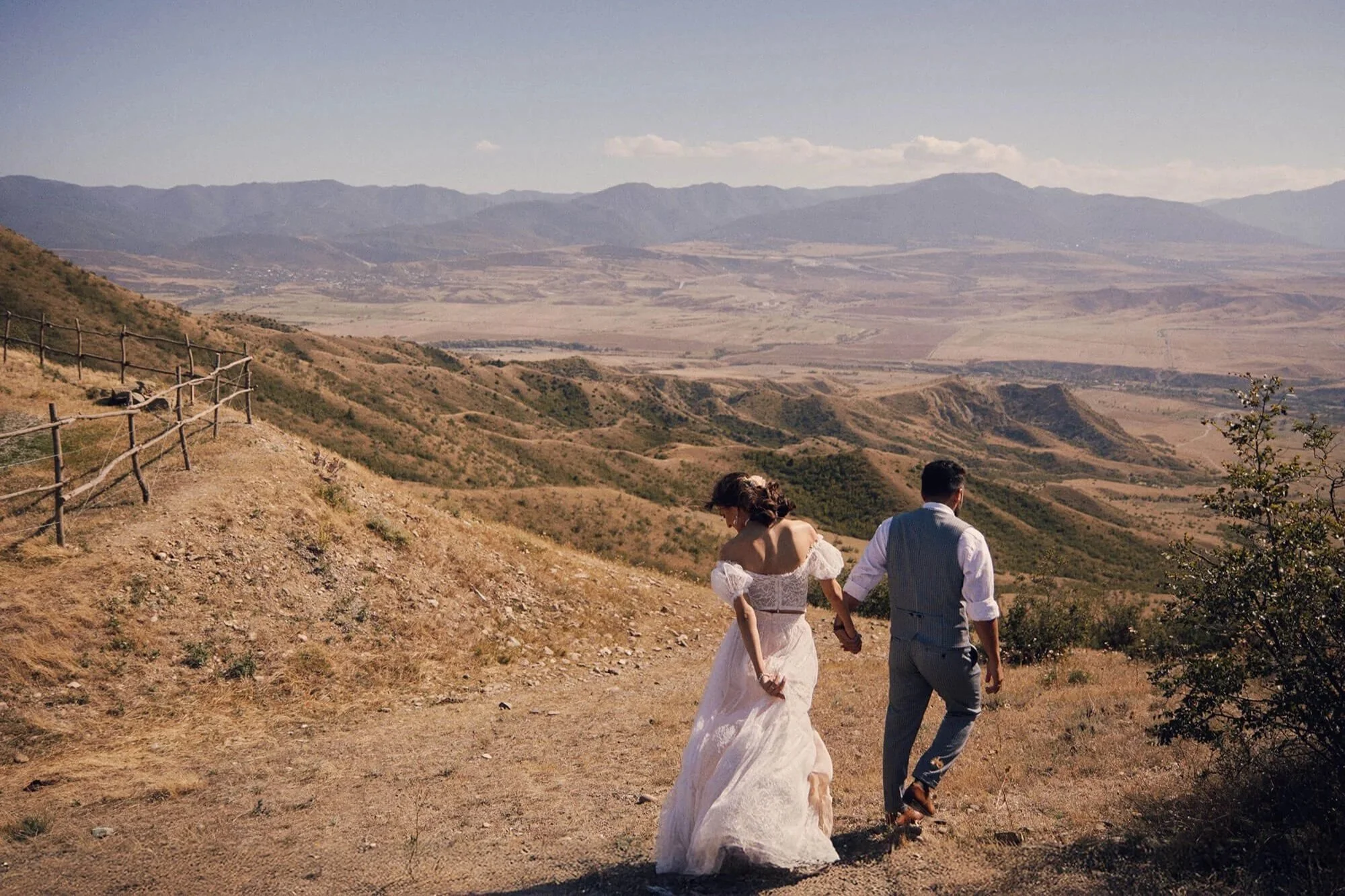 Bride and groom walking together in a beautiful mountain landscape.