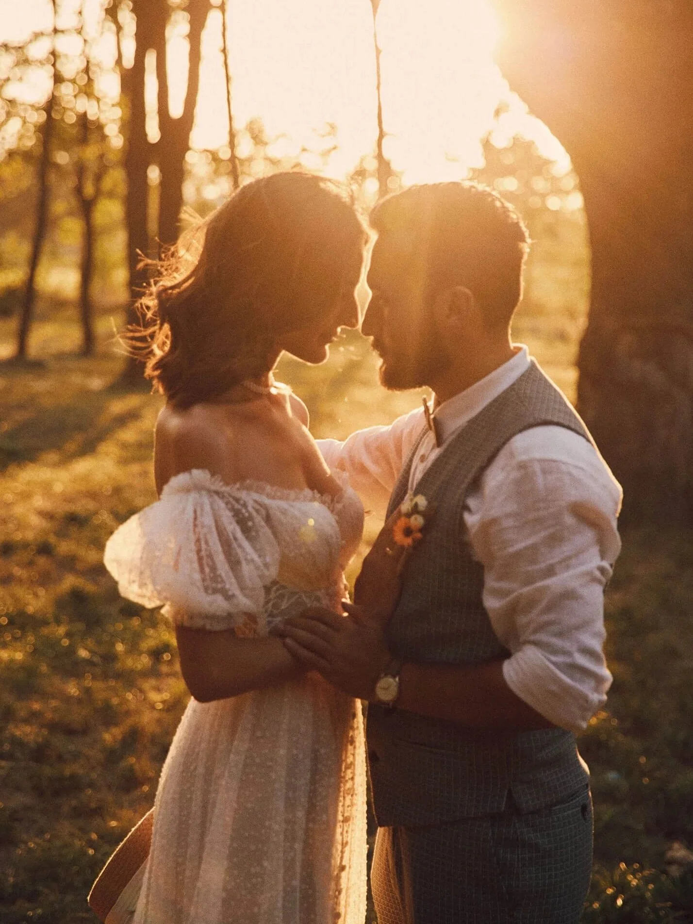 Bride and groom silhouetted by the sunset light in a forest