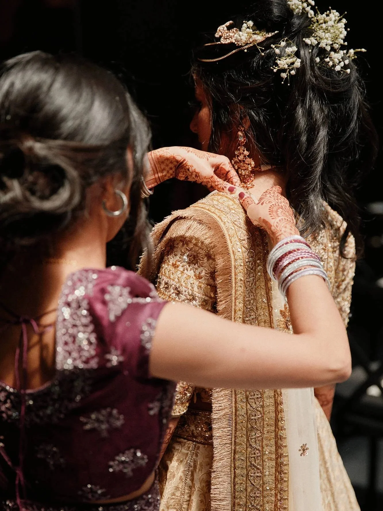 Bride getting ready, showing her ornate gold bangles and traditional attire