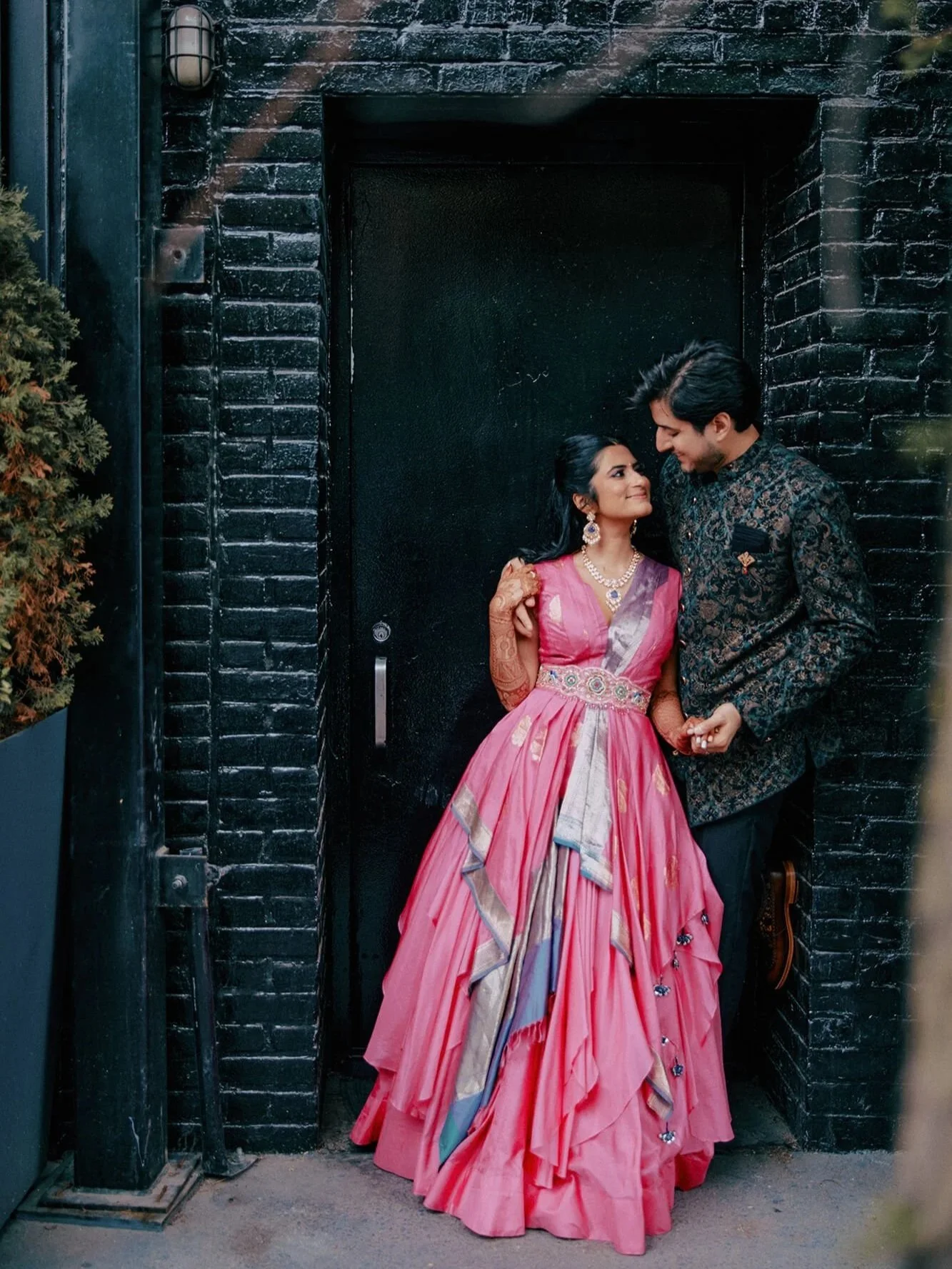 The couple in their modern reception attire, with the bride wearing a vibrant pink dress.