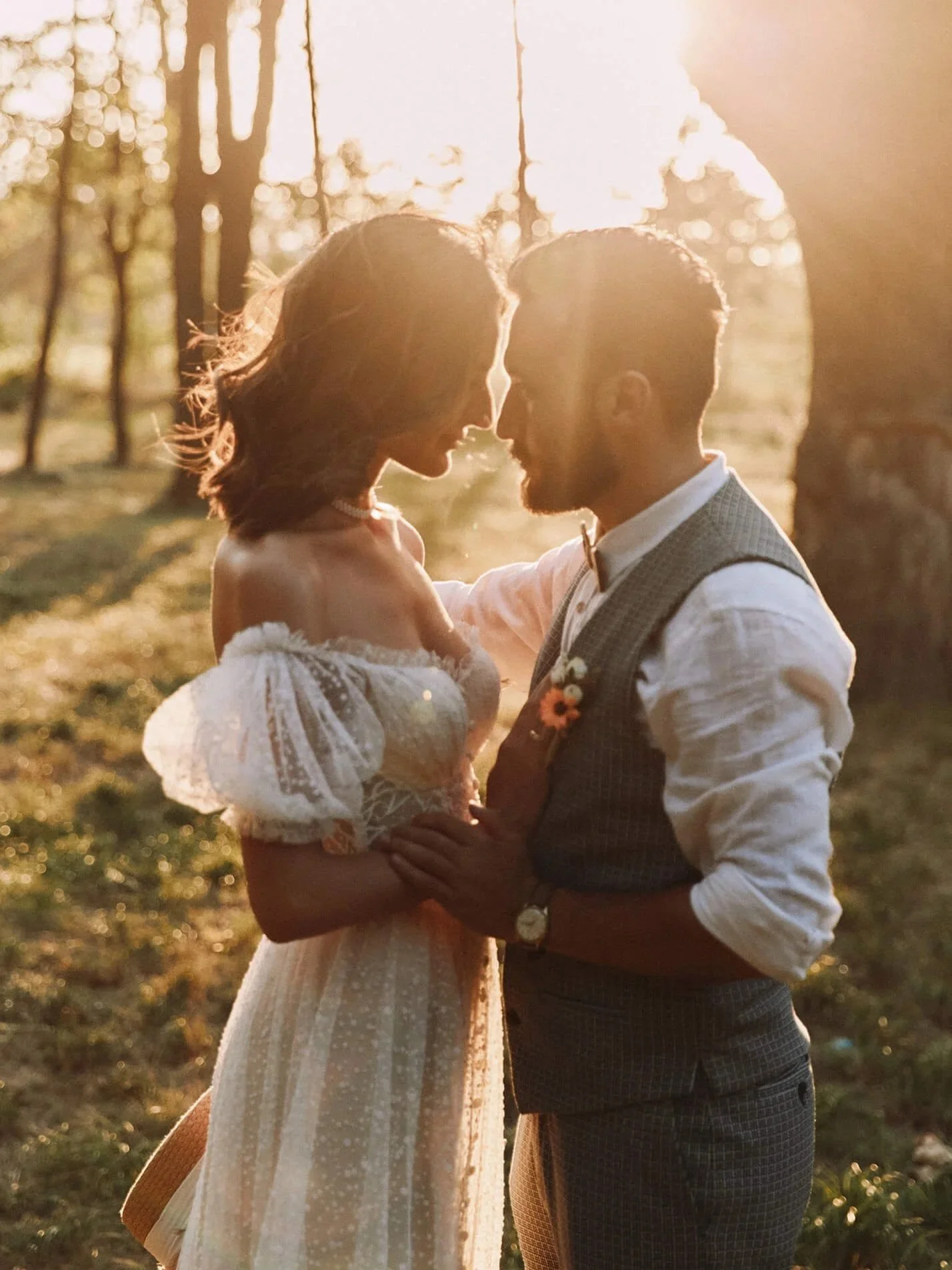 Bride and groom silhouetted by the sunset light in a forest