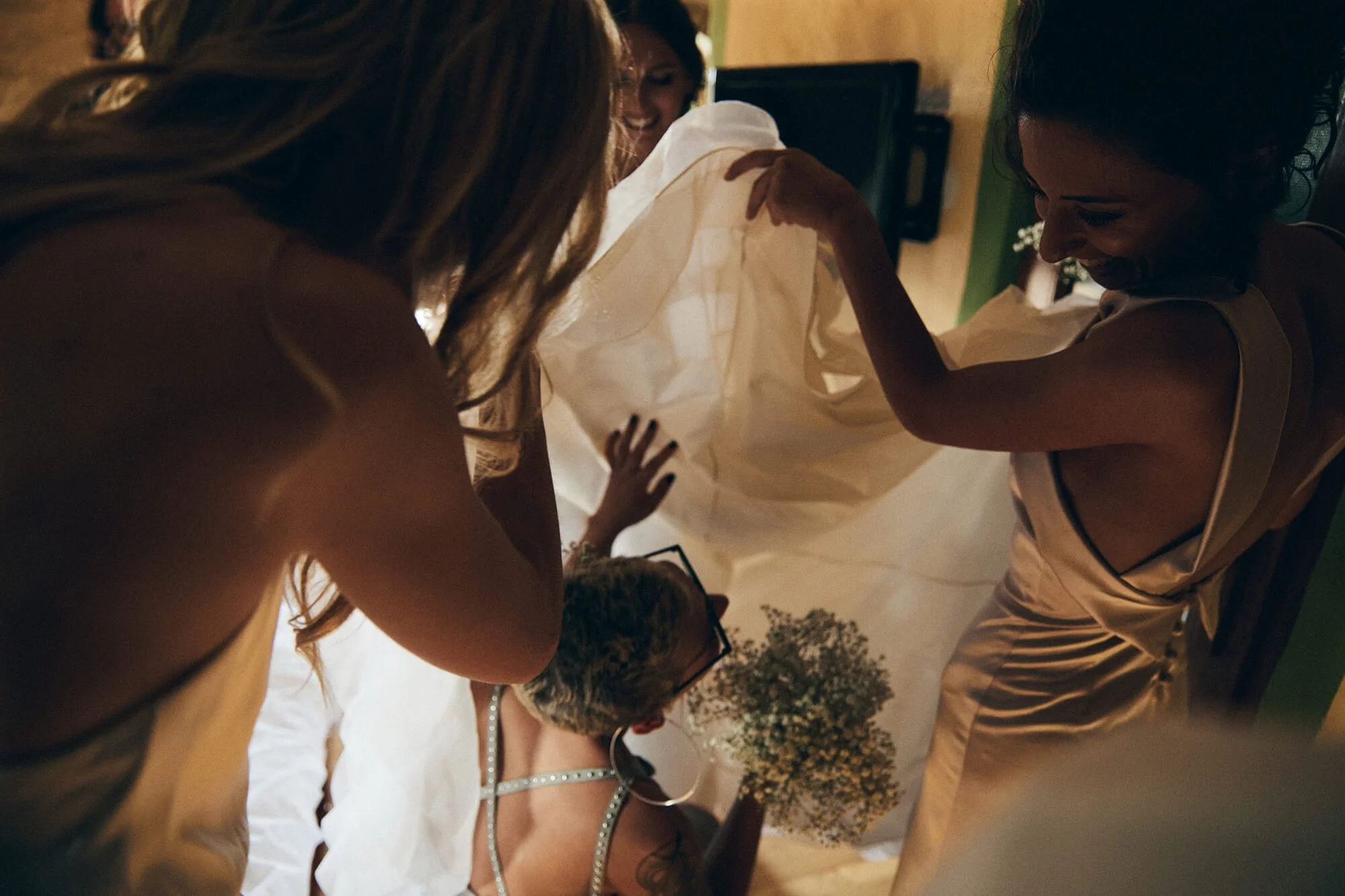 Bridal prep moment with bridesmaids fixing the gown