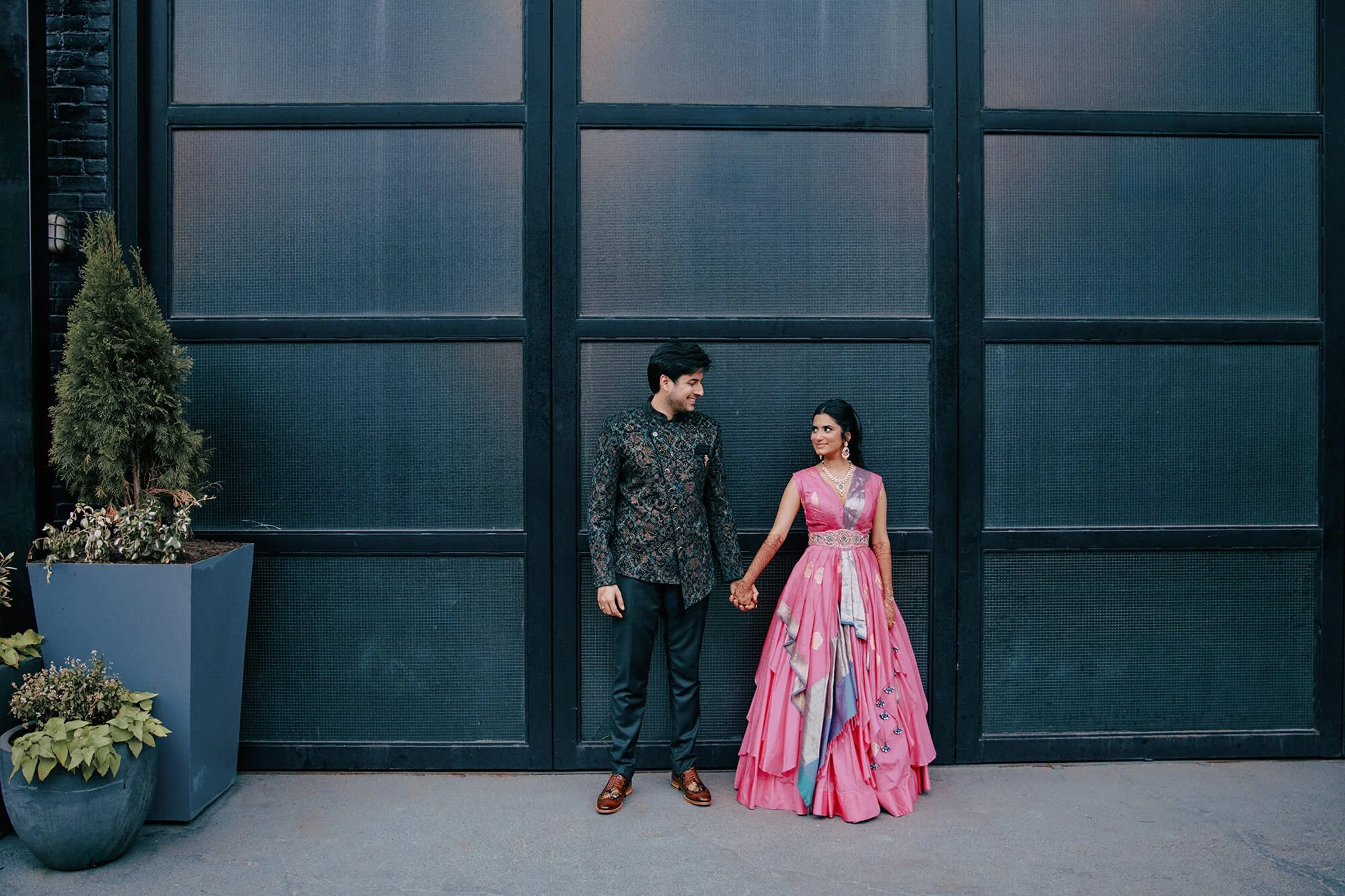 A full-length candid shot of the bride and groom in their modern reception outfits