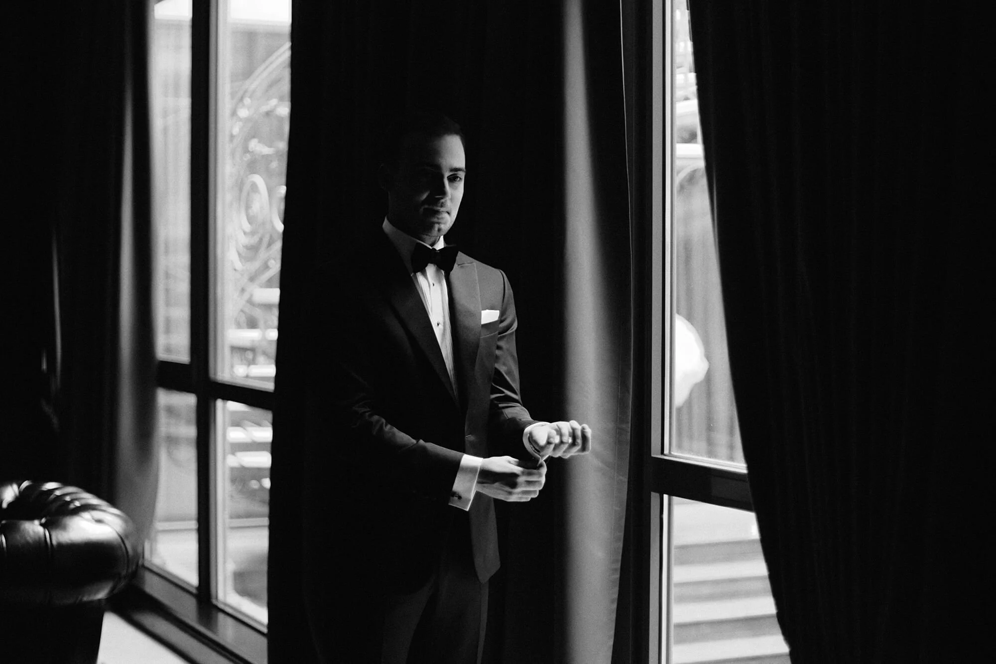 Candid black and white moment of groom getting ready