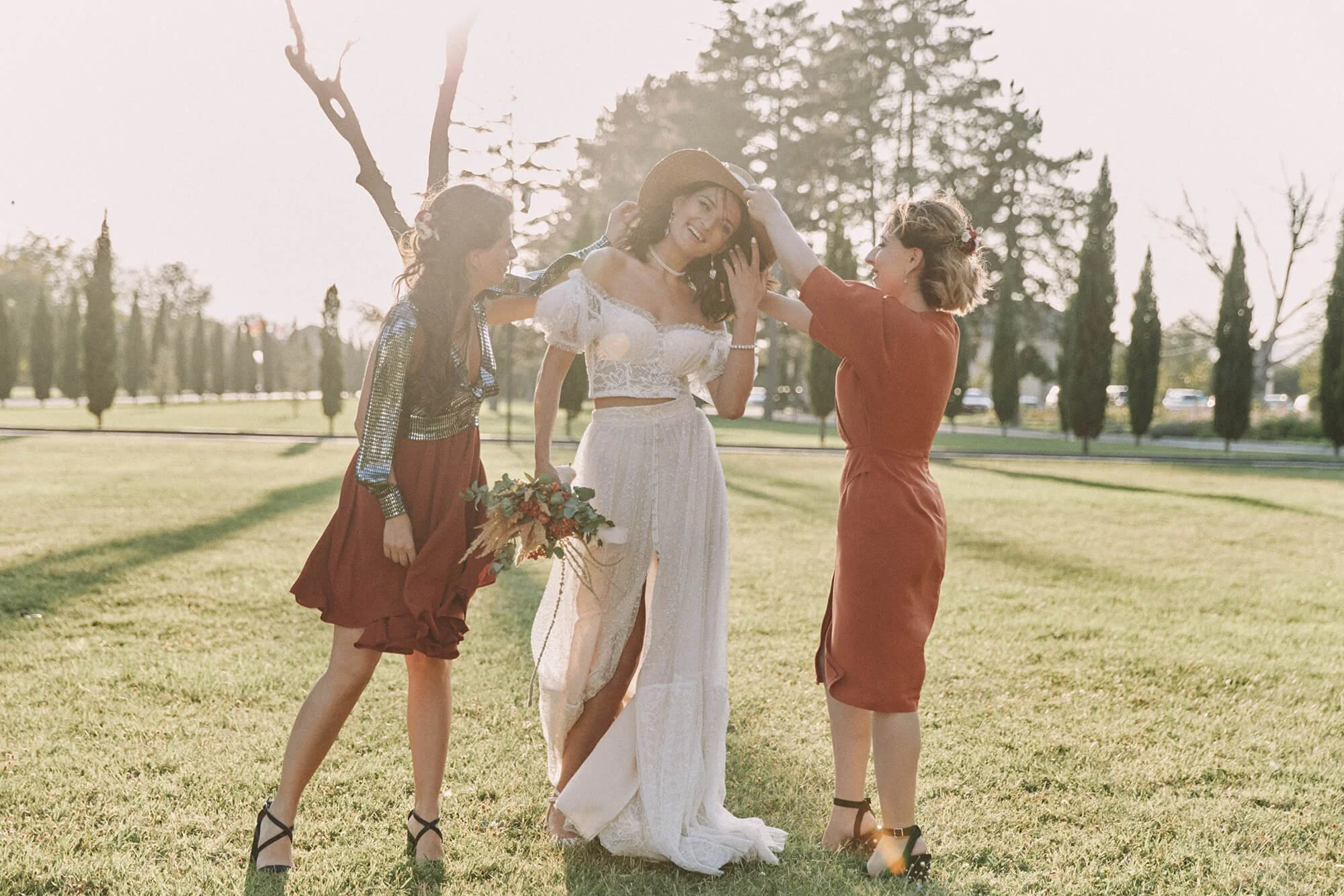 Bridesmaids helping bride with touch-ups at golden hour