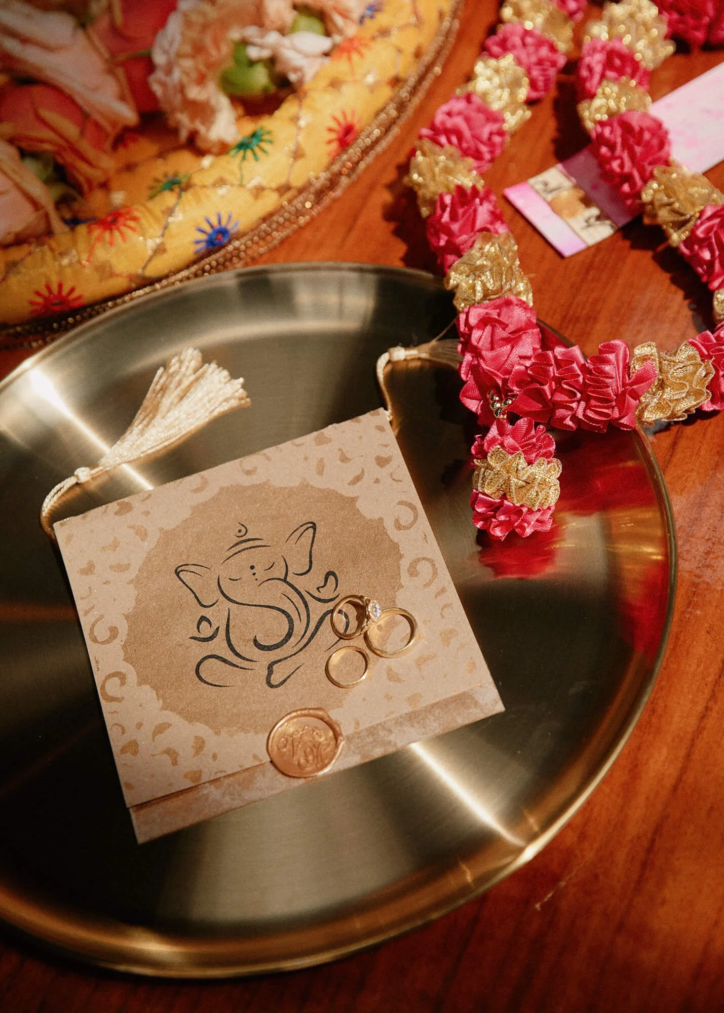 Close-up of wedding rings on a Ganesha-themed invitation card, a beautiful Indian wedding detail
