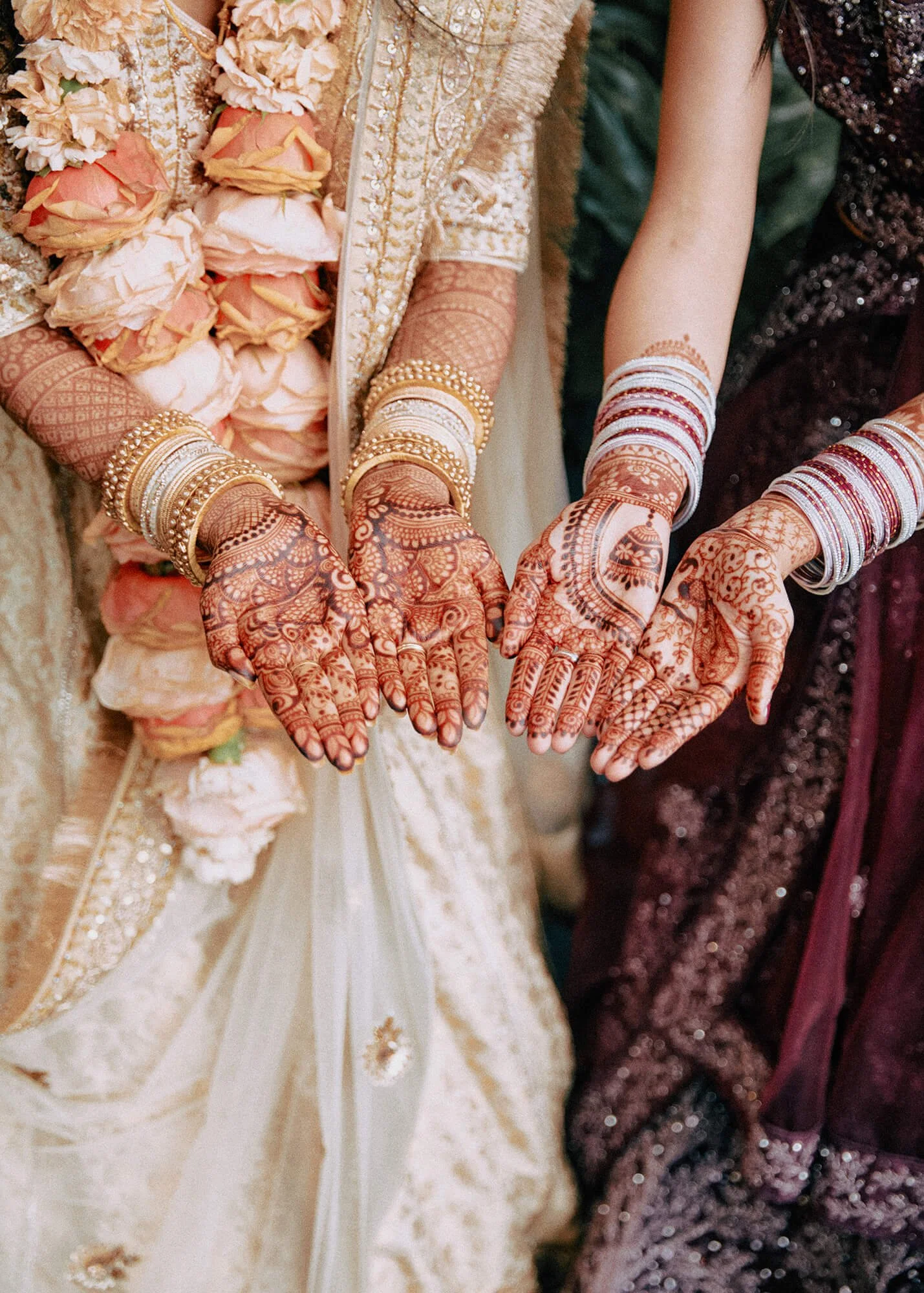 Close-up of the bride's hands adorned with intricate mehndi designs and bangles