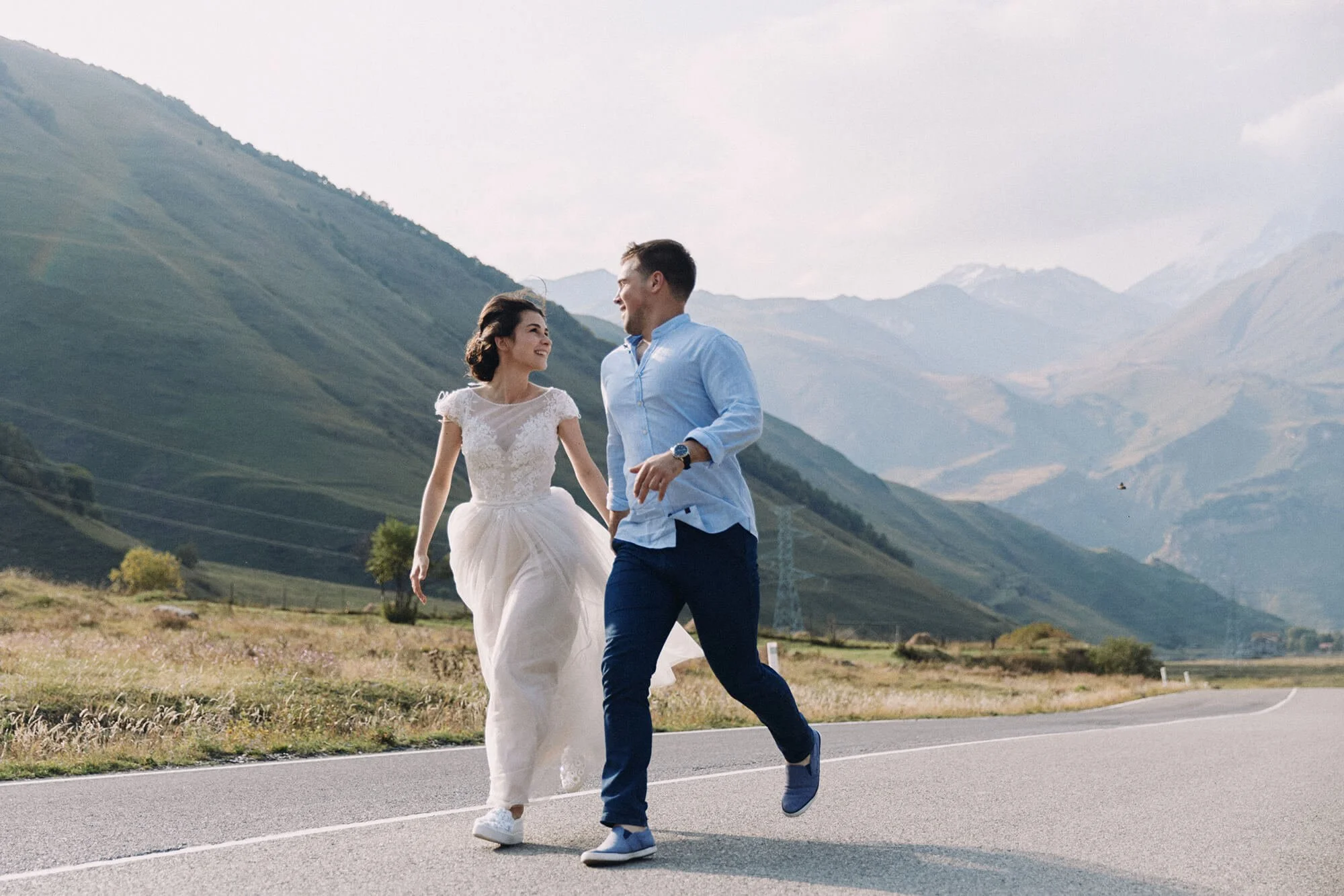 Romantic engagement moment: couple running together on open road