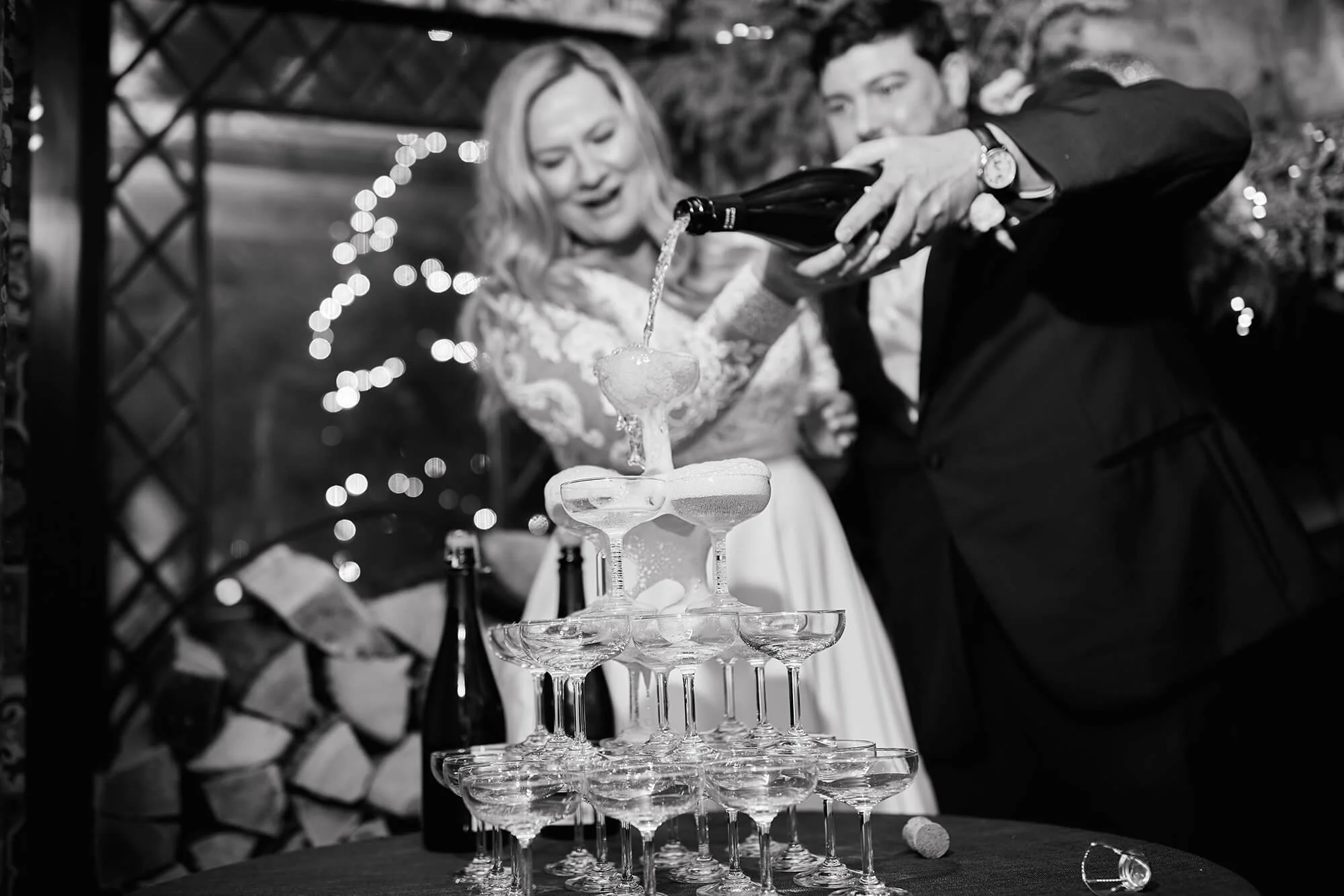 A couple pouring champagne into a tower together