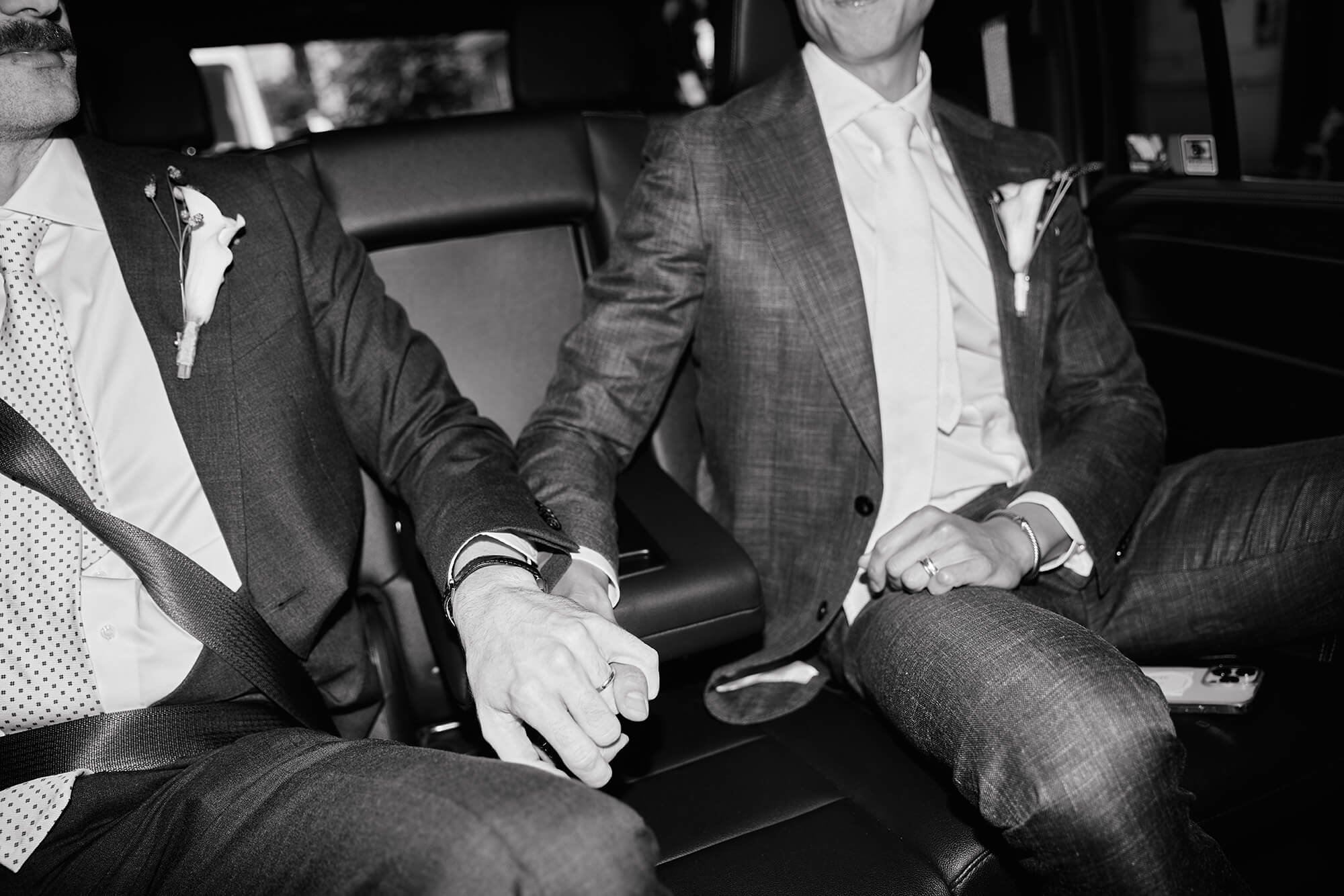 Grooms’ holding hands together in car