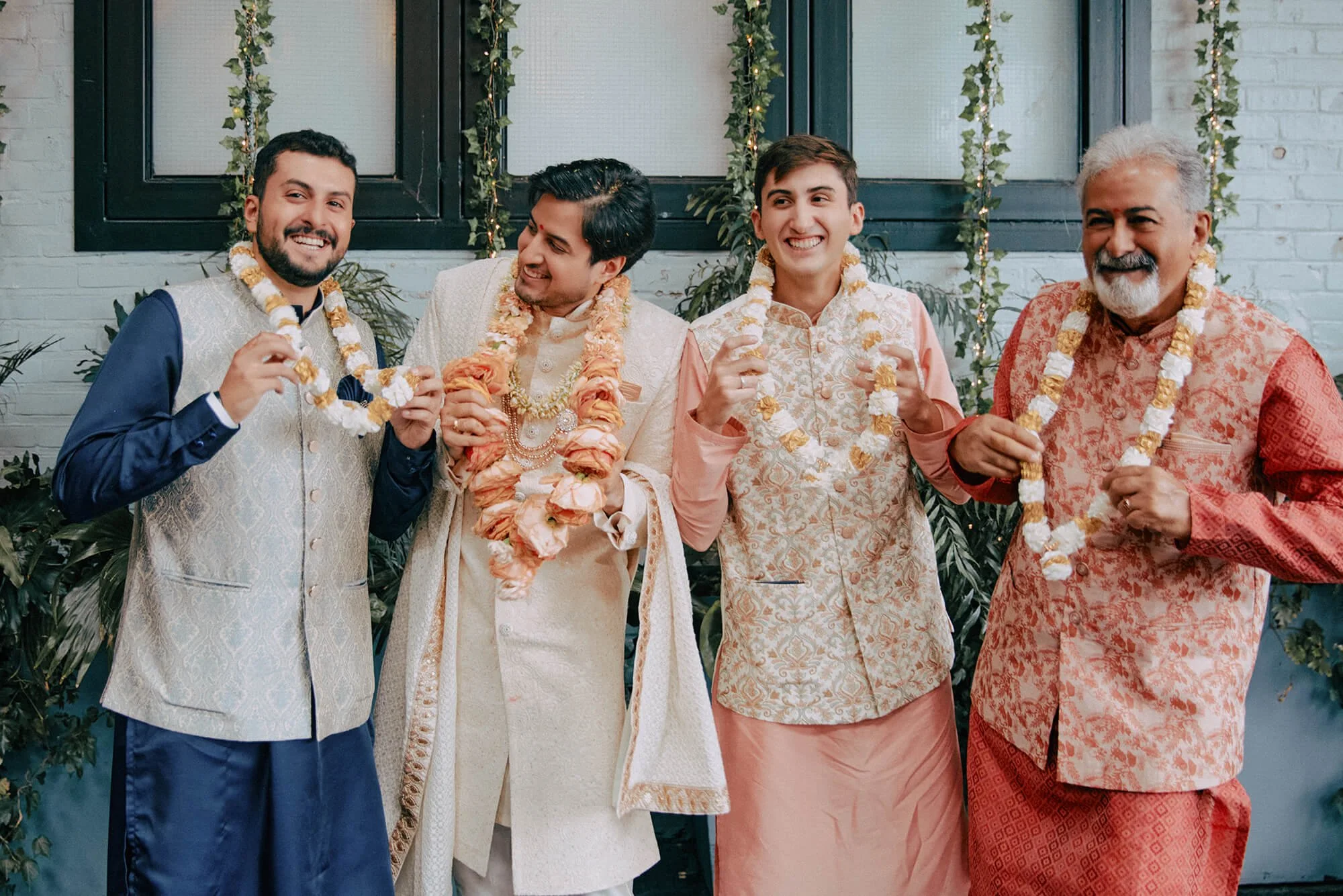 The groom and his groomsmen in traditional wedding outfits with flower garlands