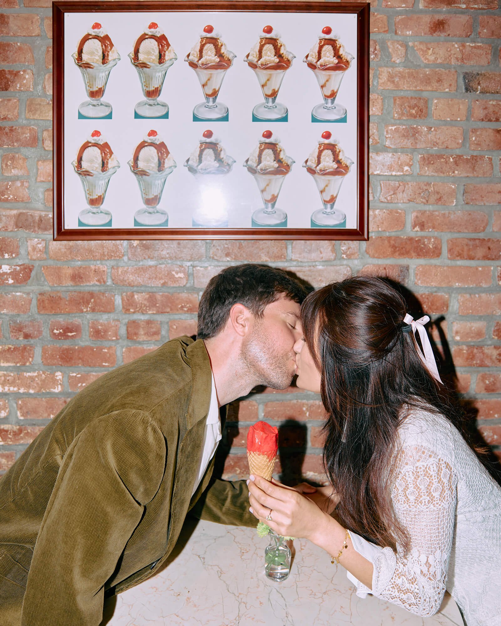 Engagement couple sharing a kiss over ice cream