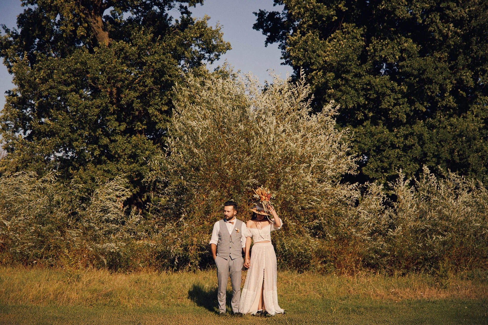 Bride and groom standing in a field of blossoms.