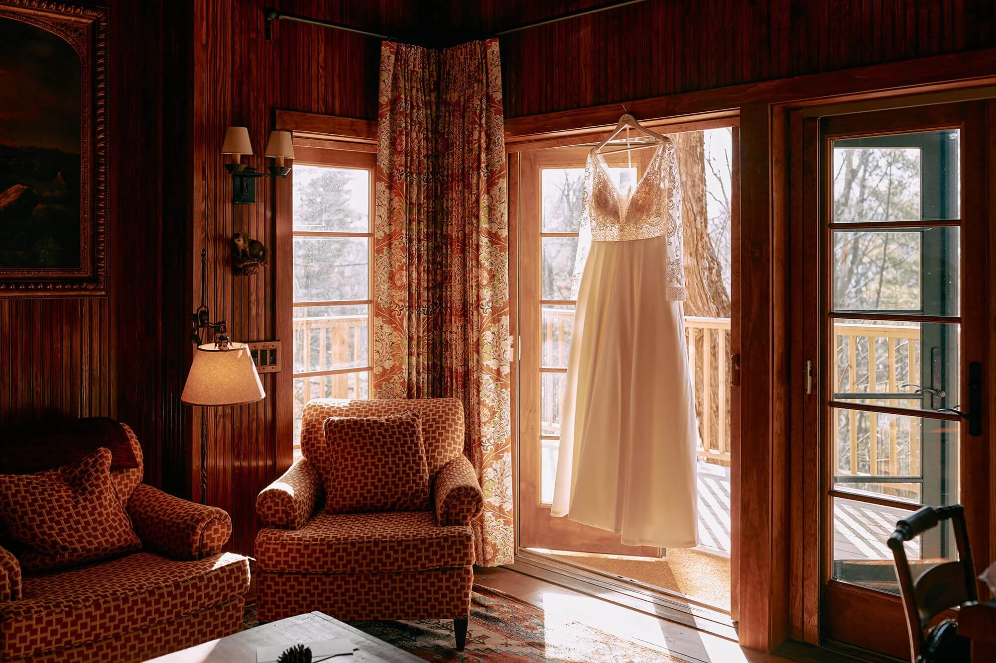 Bridal gown hanging in cozy wooden cabin light