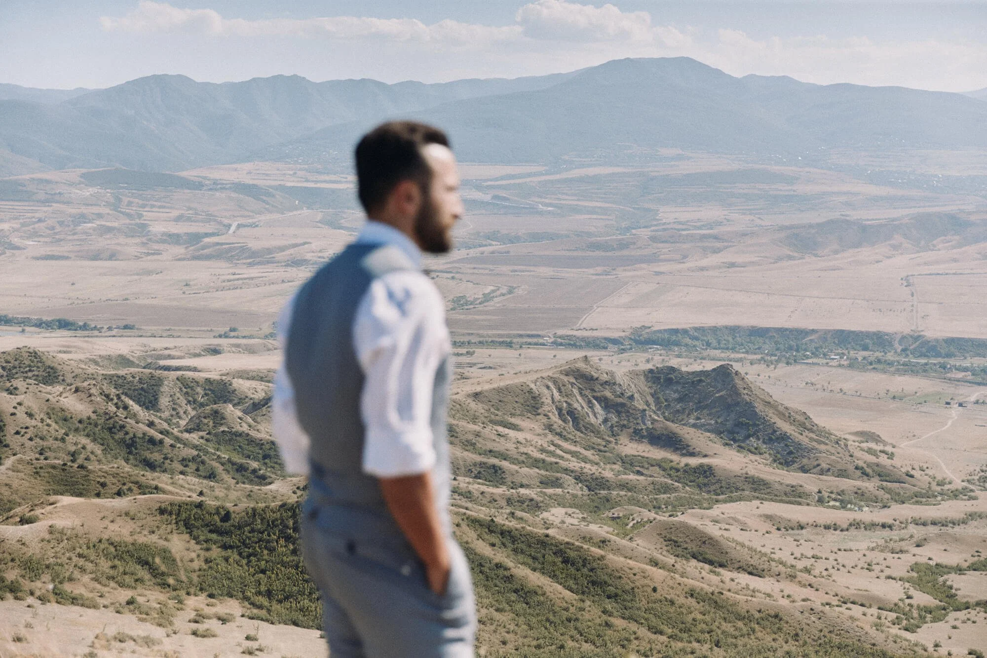 Groom looking out over a mountain landscape.