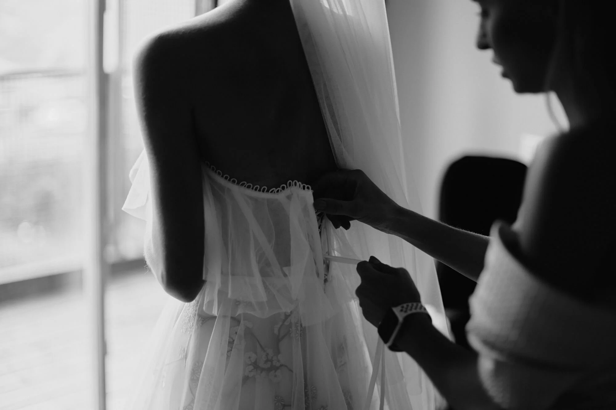 Bride getting ready by the window with her sister