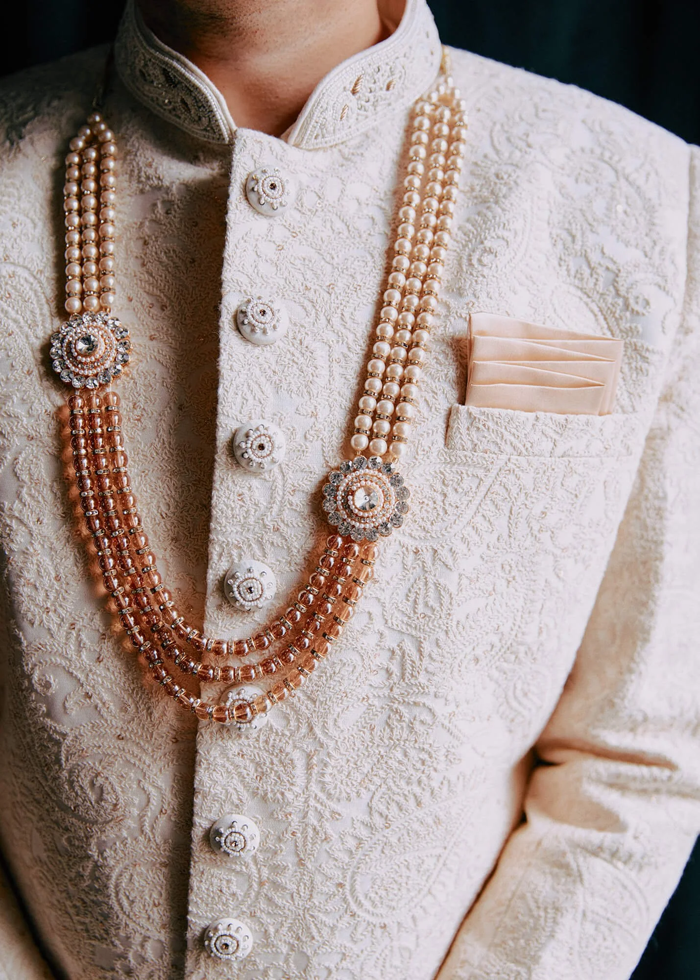Detail shot of the groom's wedding sherwani with a beaded necklace and pocket square