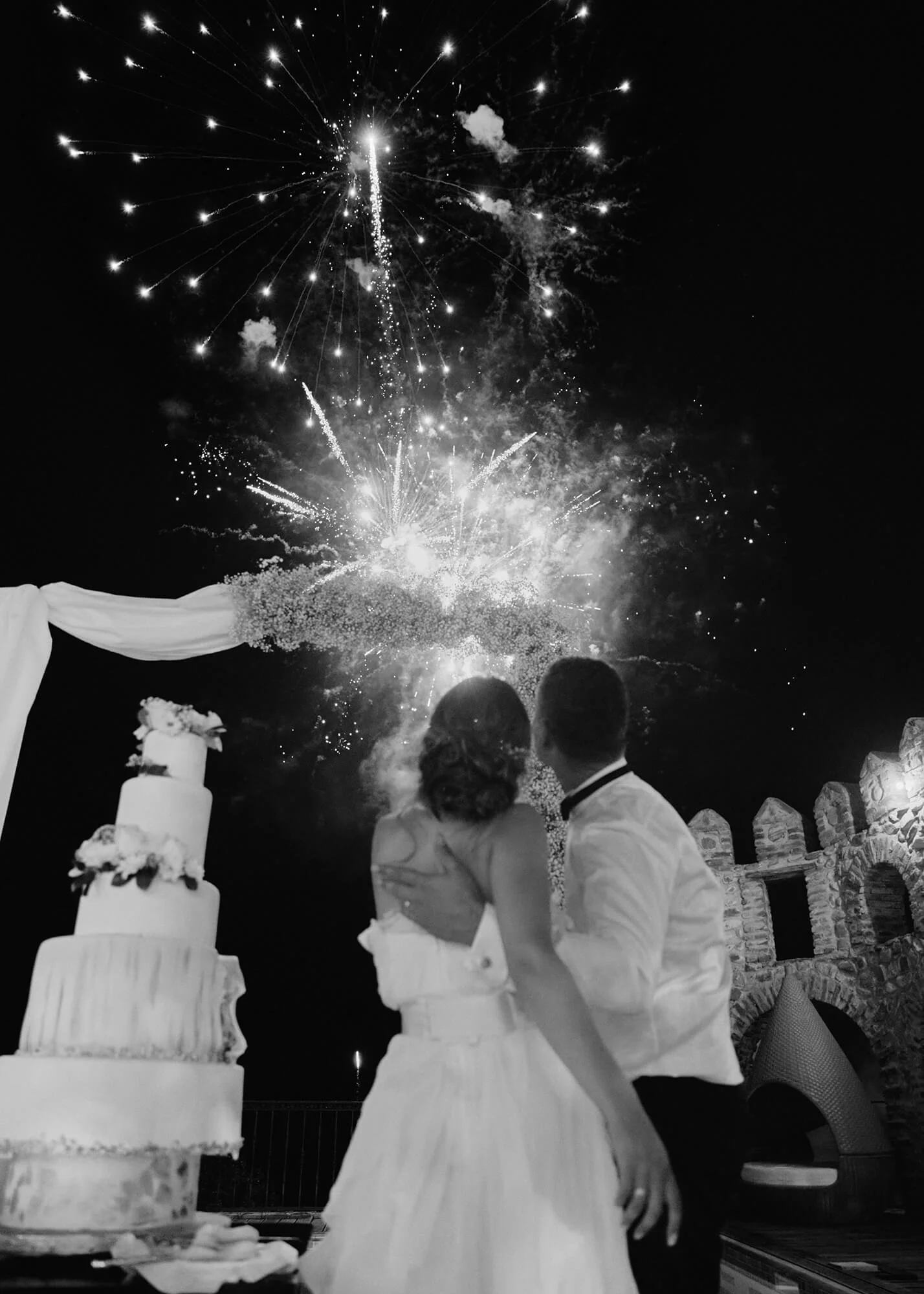 Newlyweds enjoying fireworks near wedding cake