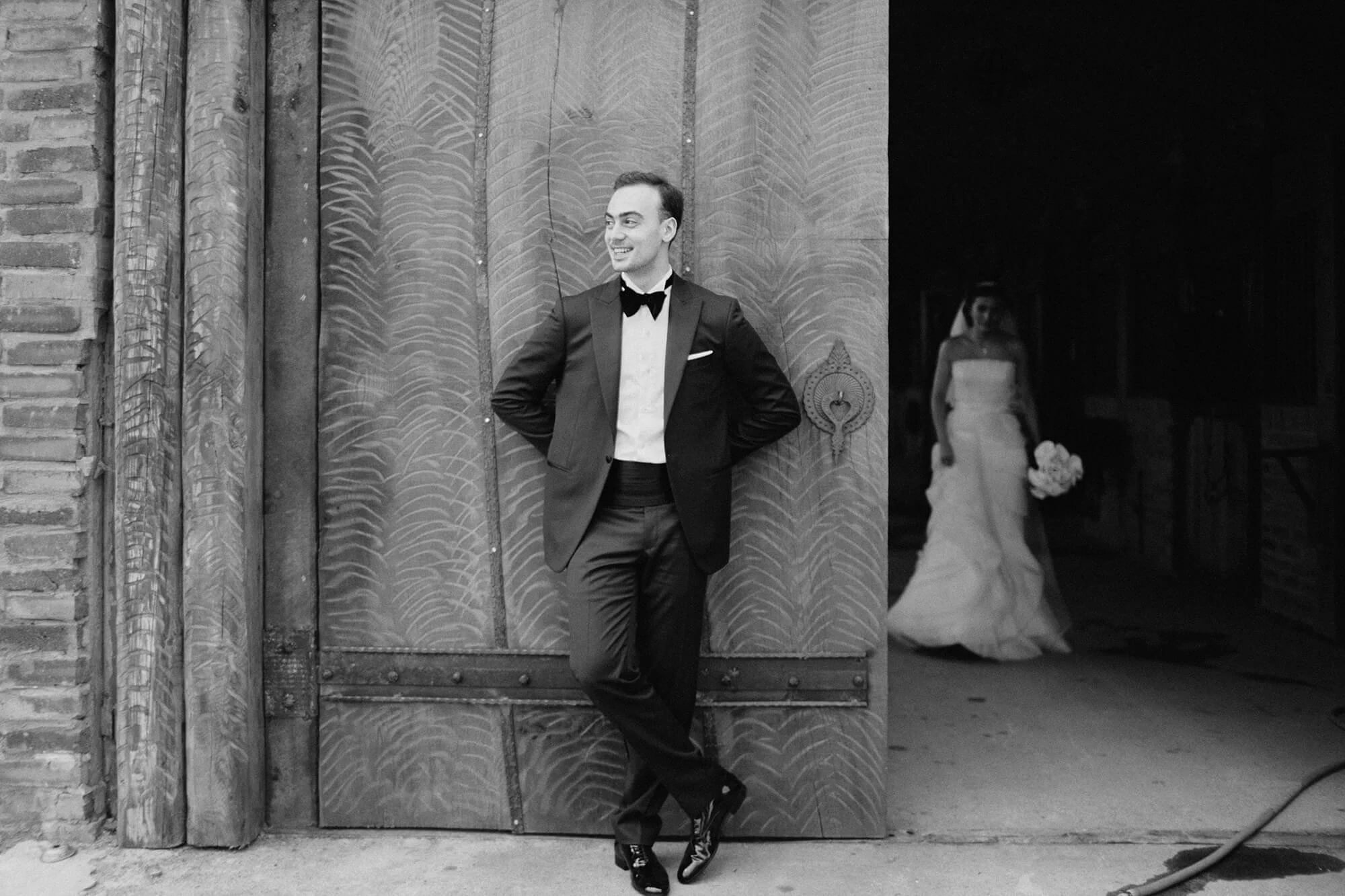 Candid wedding photography of couple by barn exterior