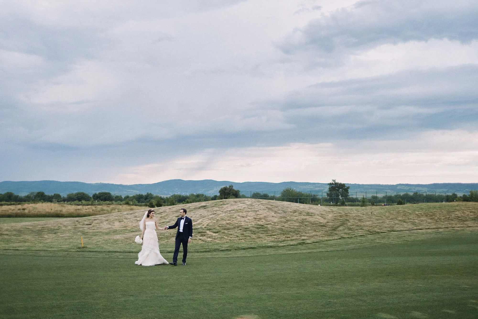 Candid engagement shot of couple walking on golf course