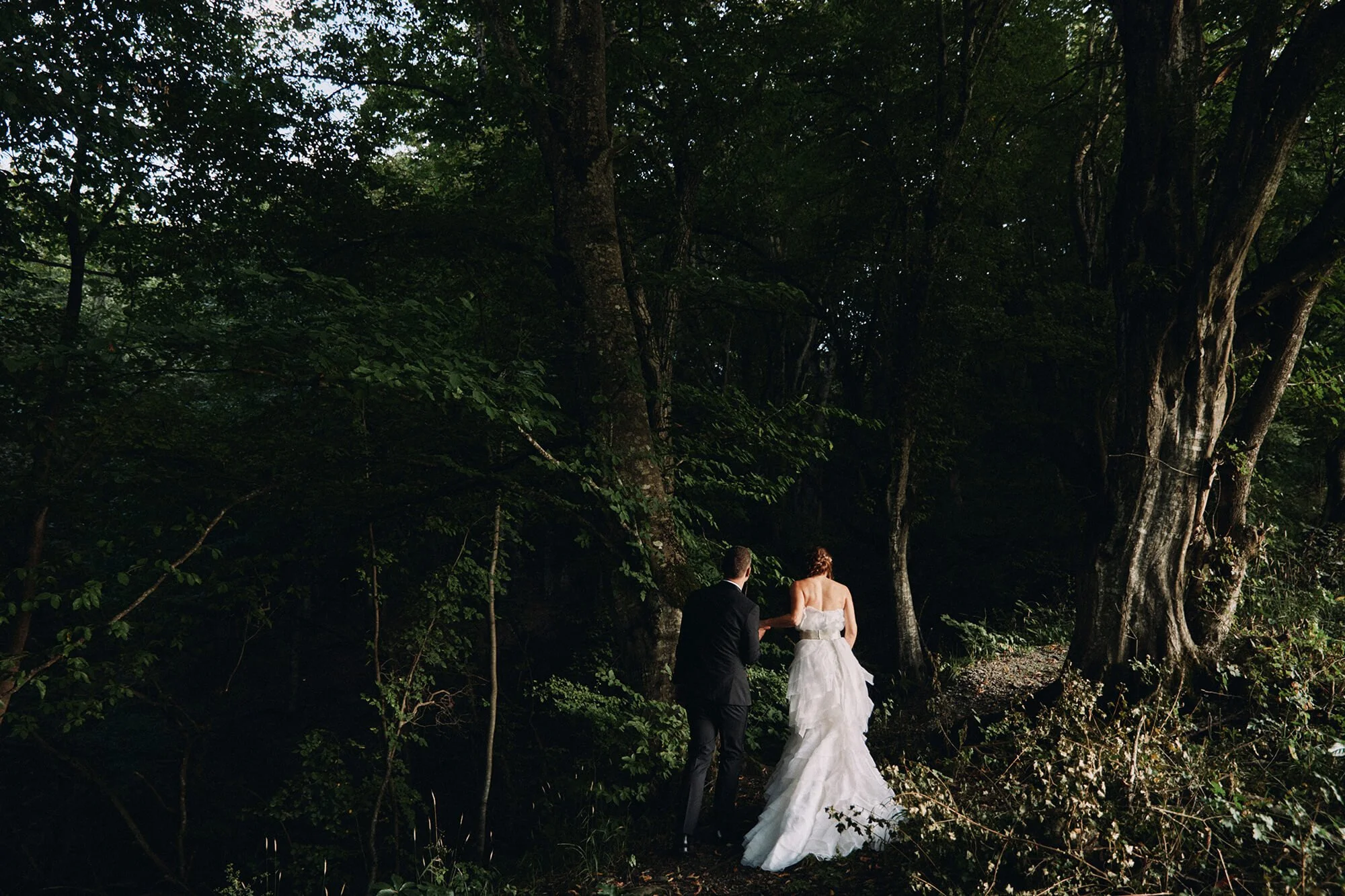 Bride and groom walking alone through the forest