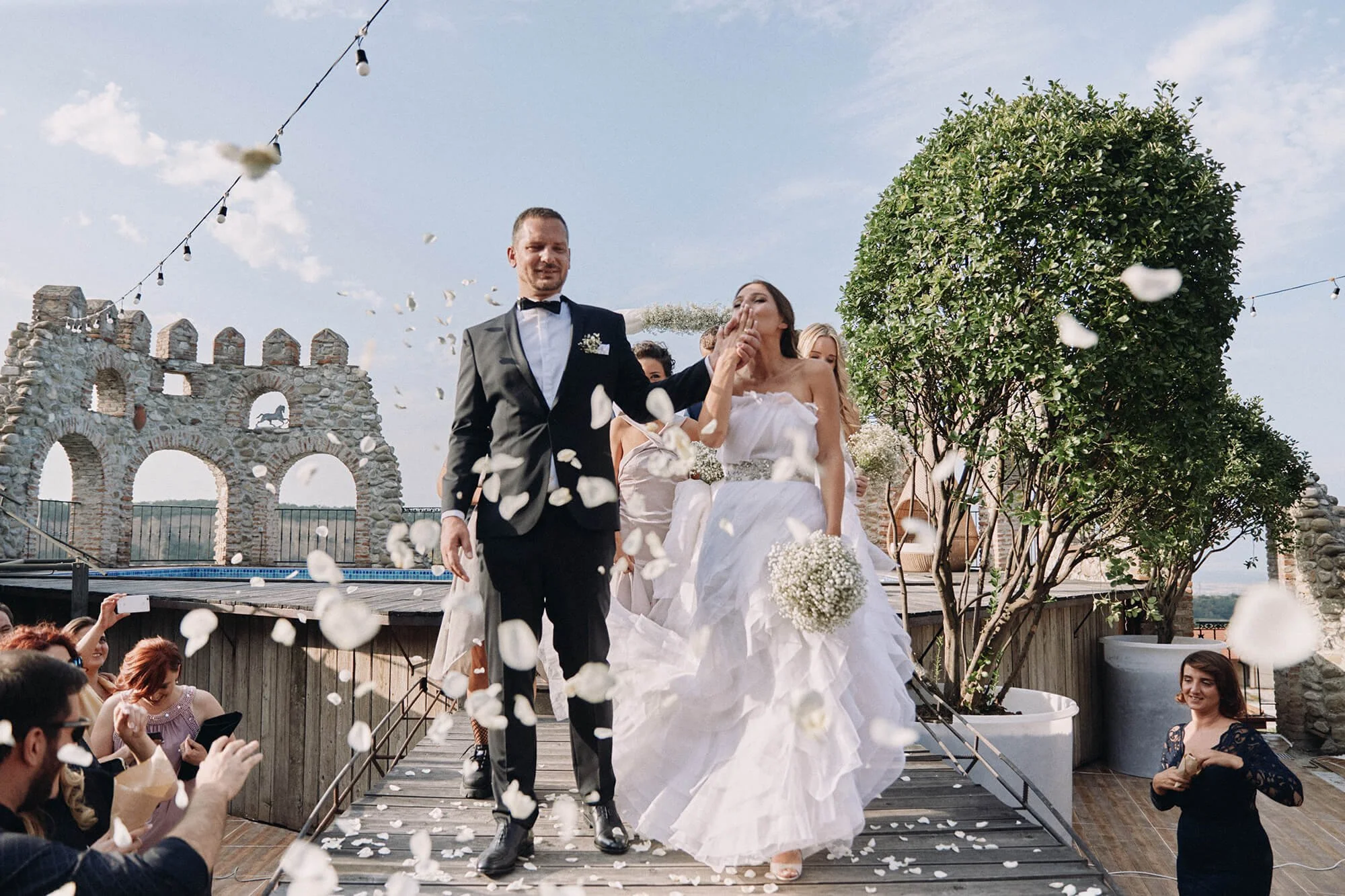 Bride and groom exiting ceremony as guests toss flower petals
