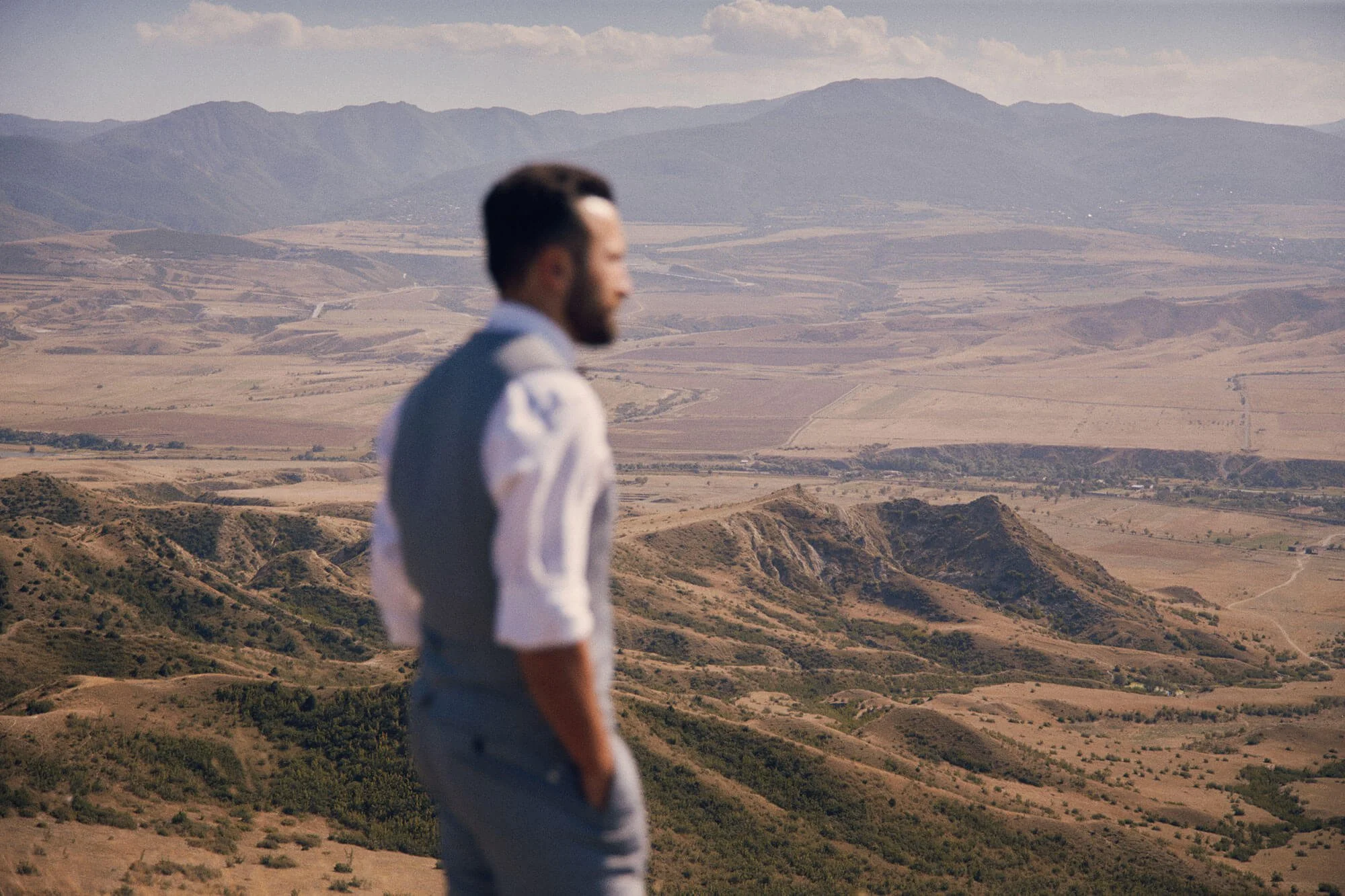 Groom looking out over a mountain landscape.