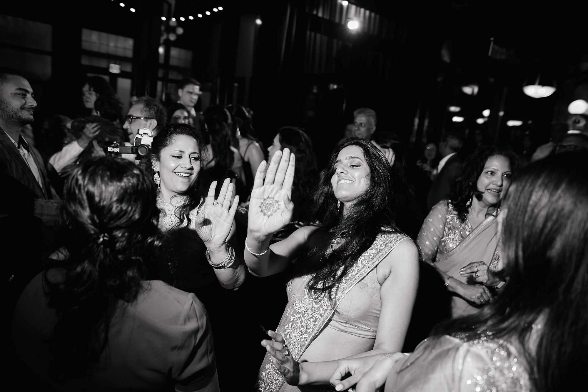 A candid black and white photo of guests dancing at the wedding