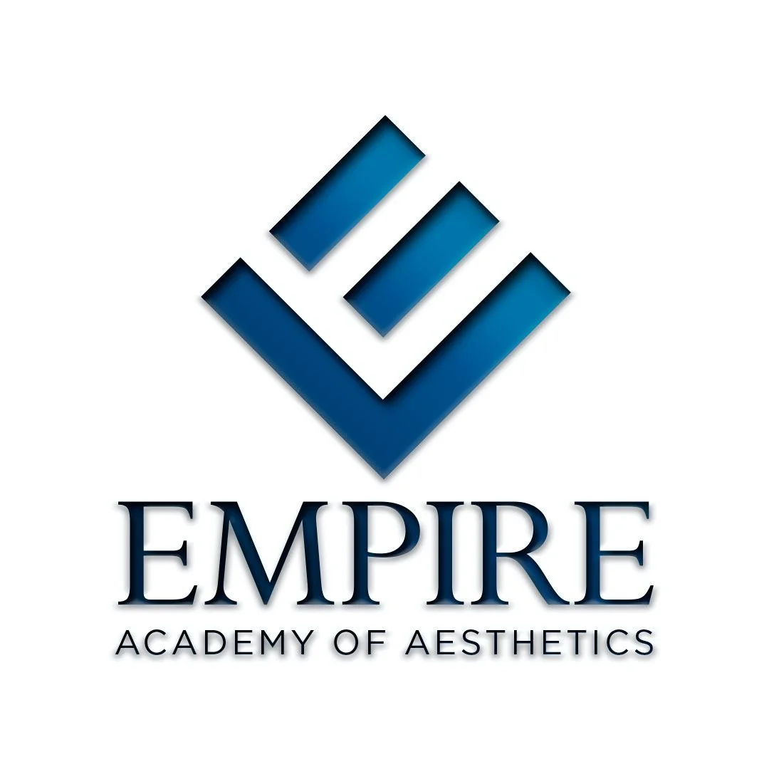 Person smiling with dark hair and blue shirt in front of greenery.