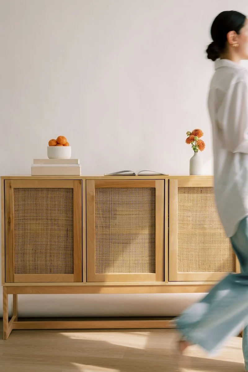 Woman walking past a console table with fresh fruit, reflecting approachable, everyday naturopathic care that fits real life