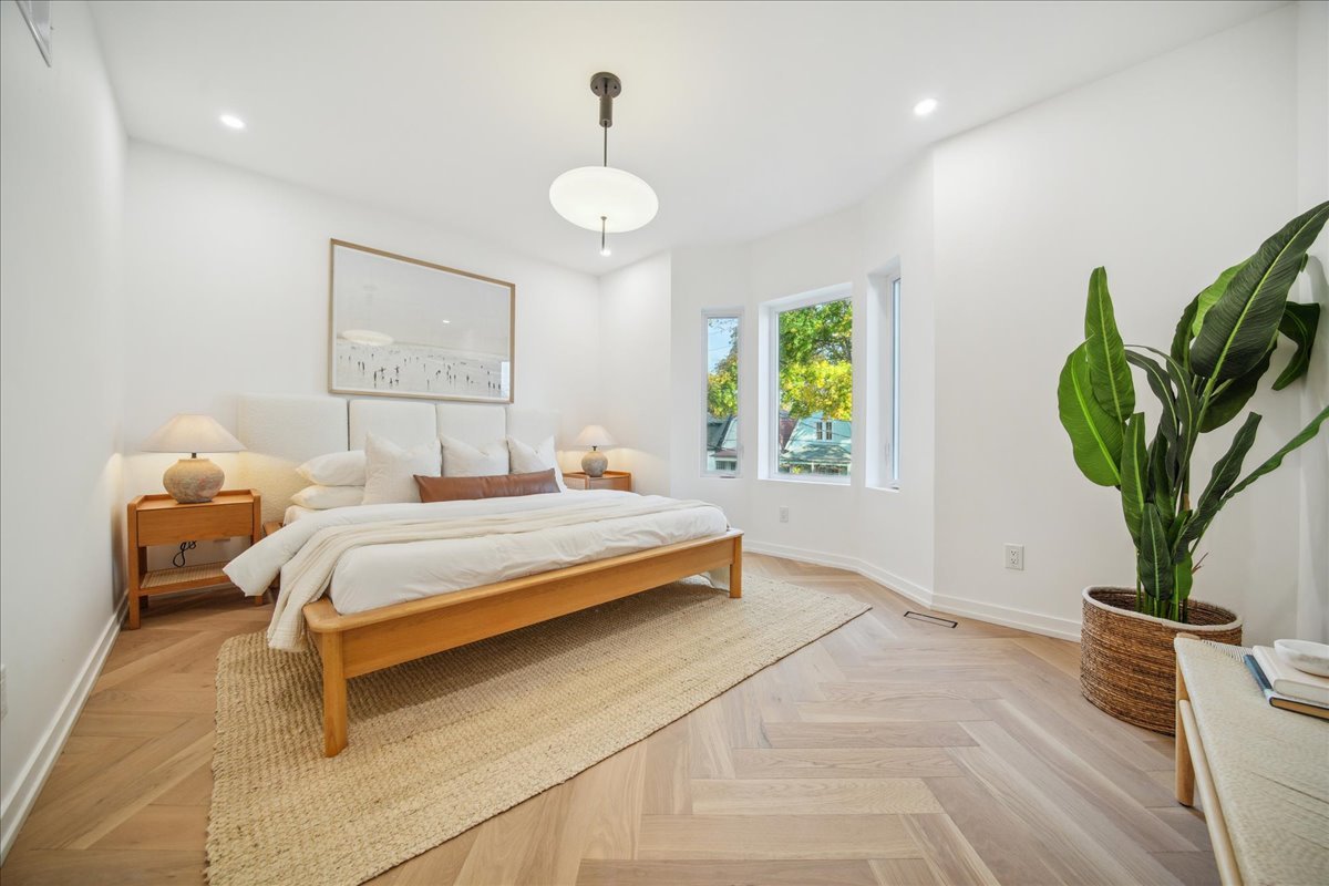 Modern bedroom with white walls, wooden bed, and greenery