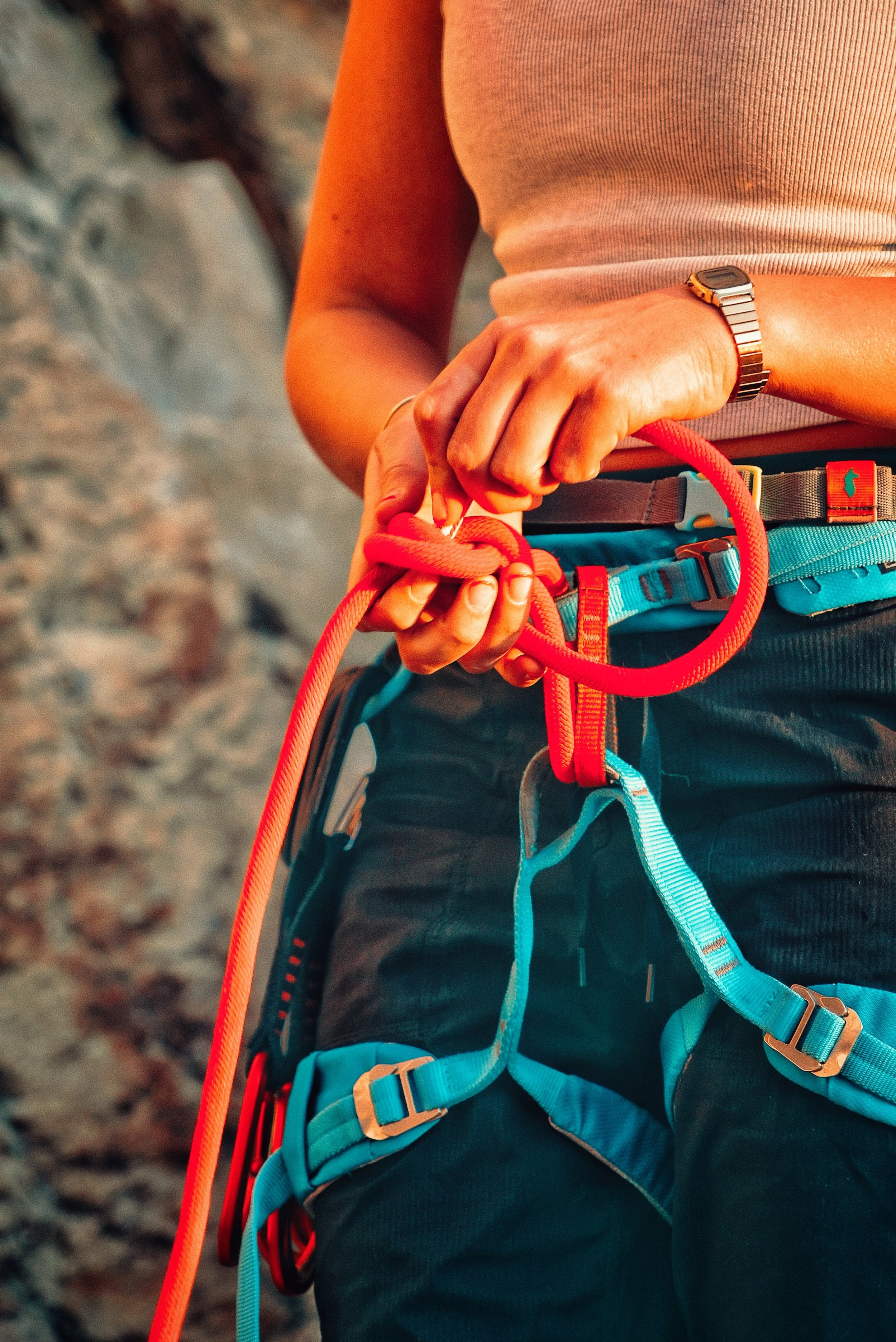 Close-up of a person's waist, hands, and climbing gear while rock climbing outdoors.