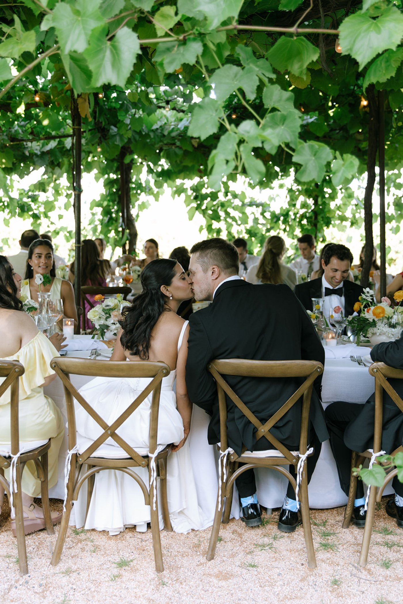 Bride and groom kissing each other at the dinner table during their wedding reception