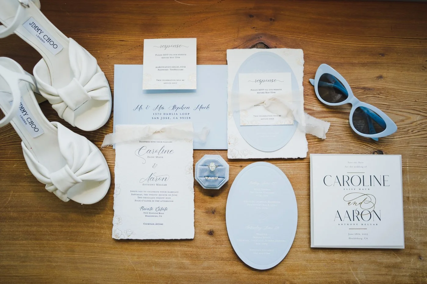 Flatlay of a white and light blue wedding invitation and Jimmy Choo heels