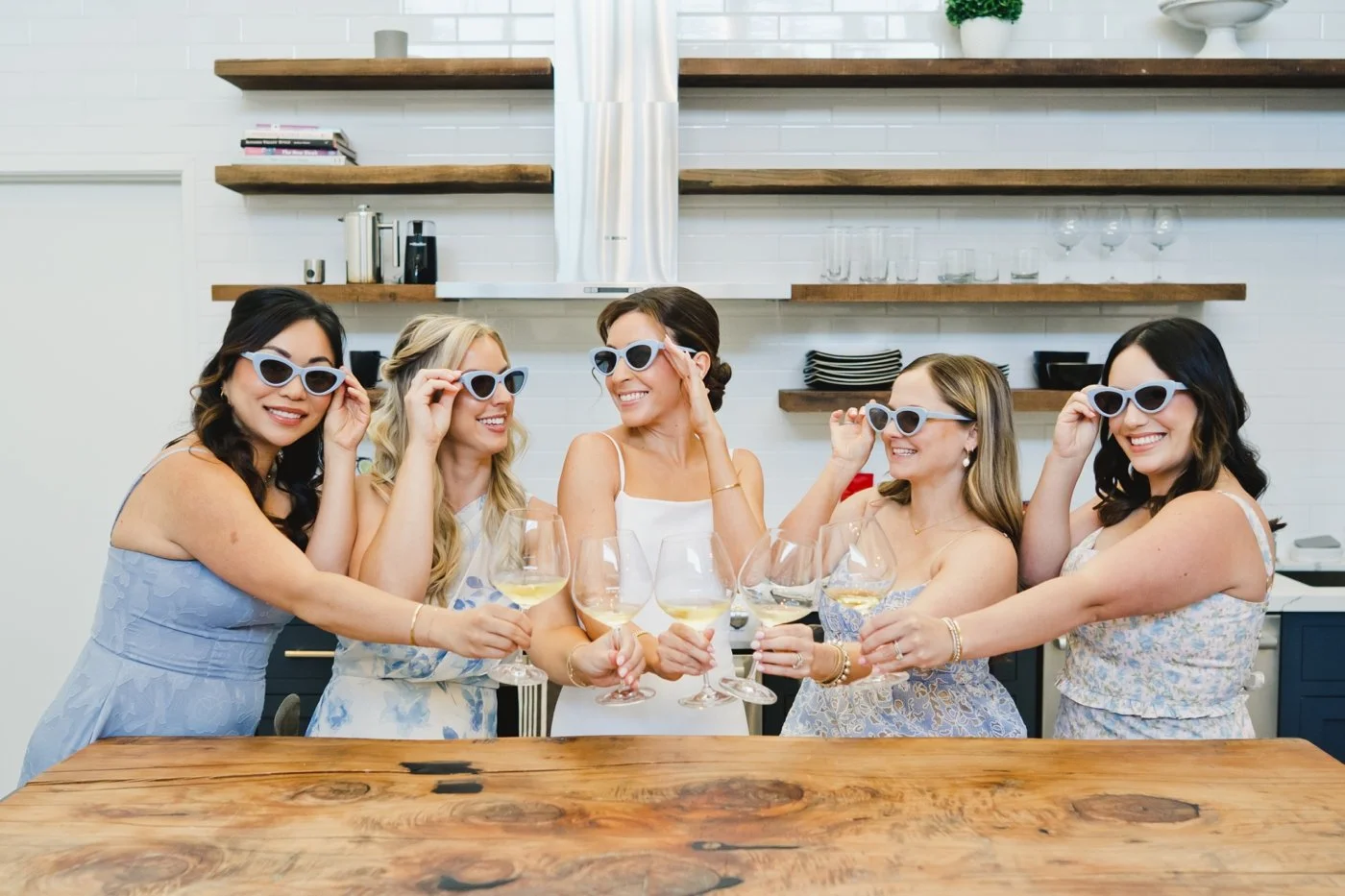 Bride drinking wine with her bridesmaids and wearing light blue cat eye sunglasses