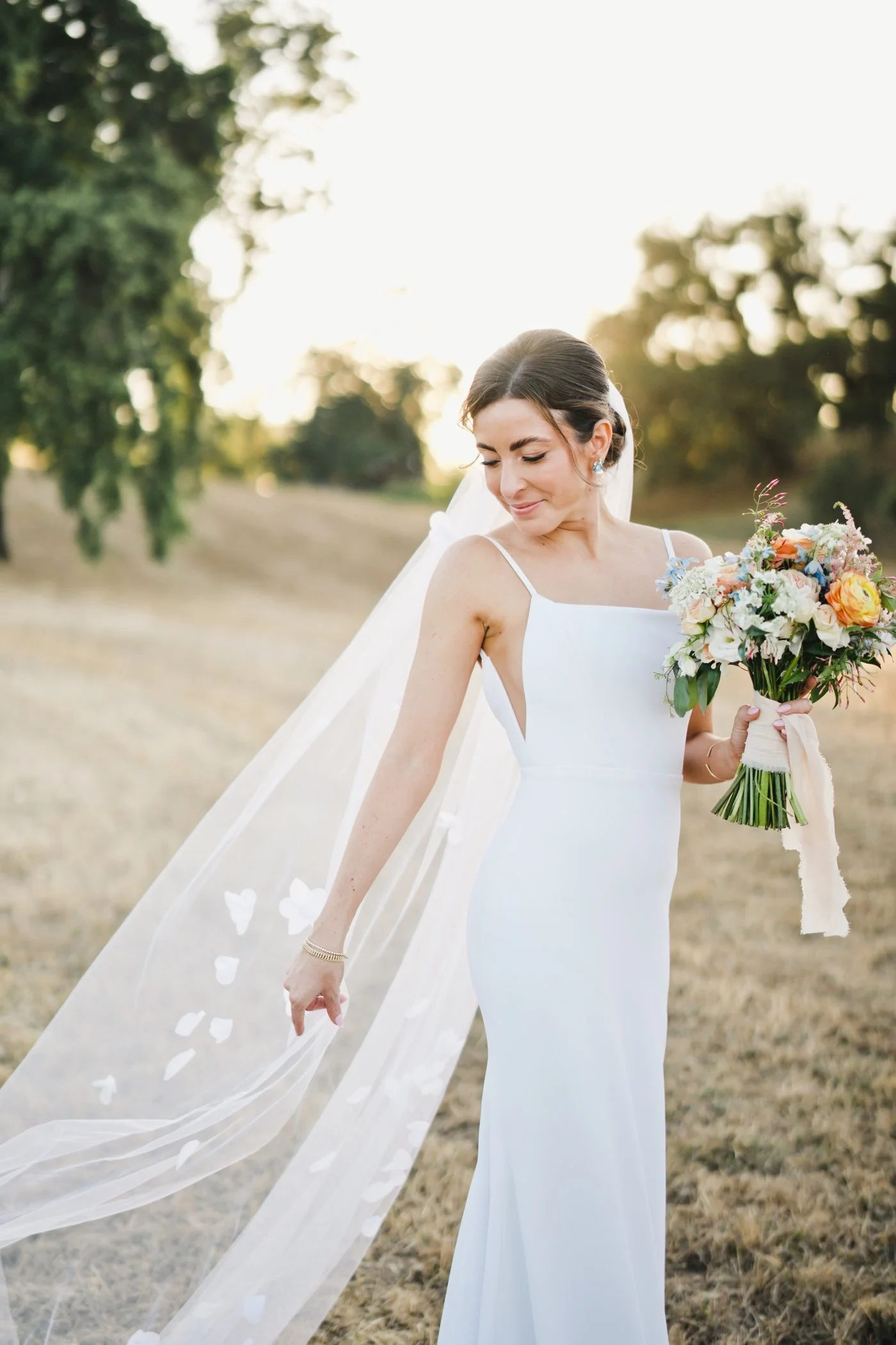 Bride looking over her shoulder at her veil and holding her bridal bouquet