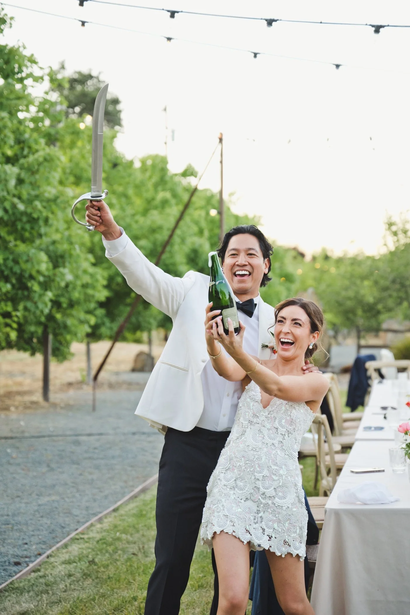Bride and groom opening a bottle of champagne with a saber